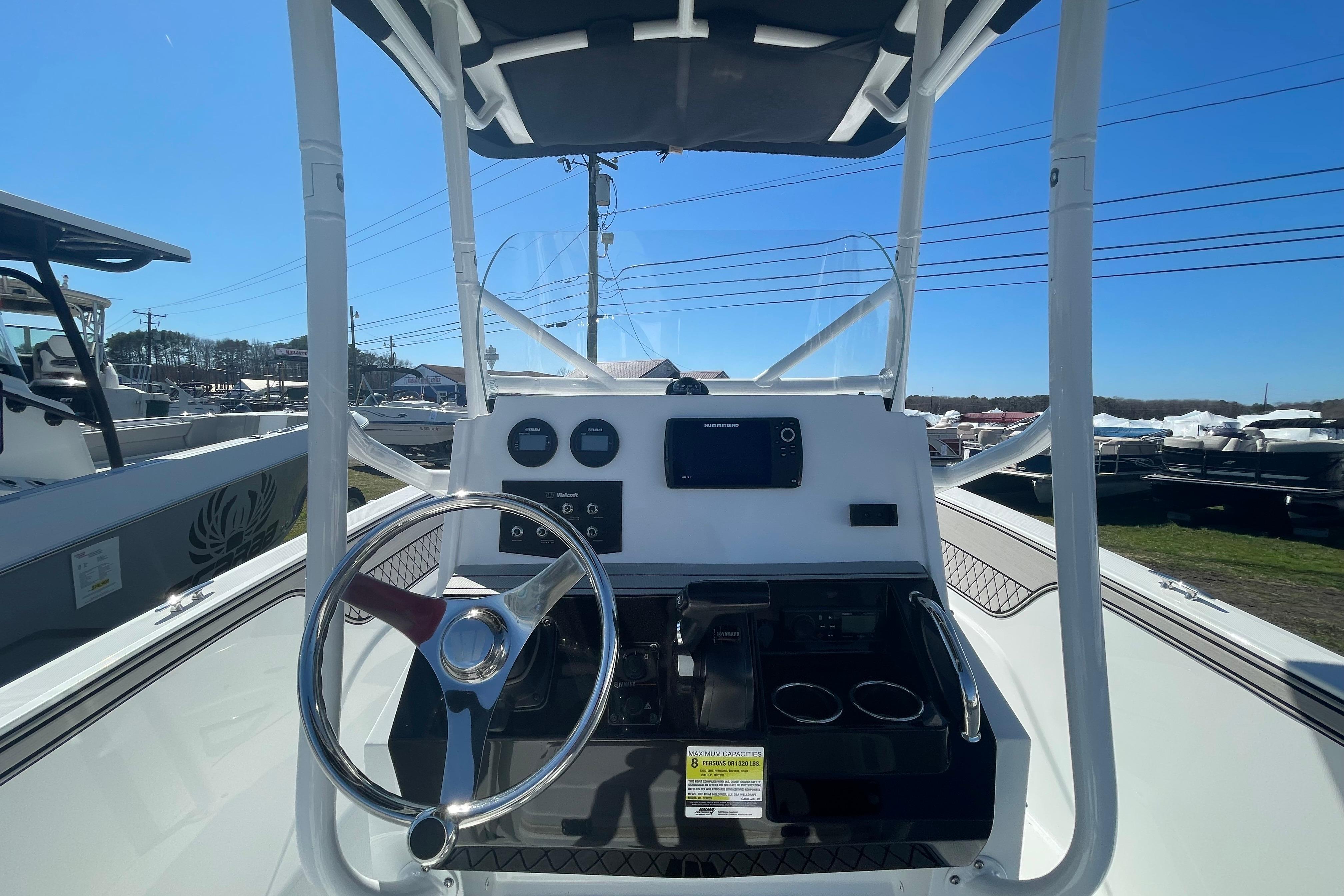 2022 Wellcraft 202 Fisherman boat dashboard with steering wheel and controls under clear blue sky.
