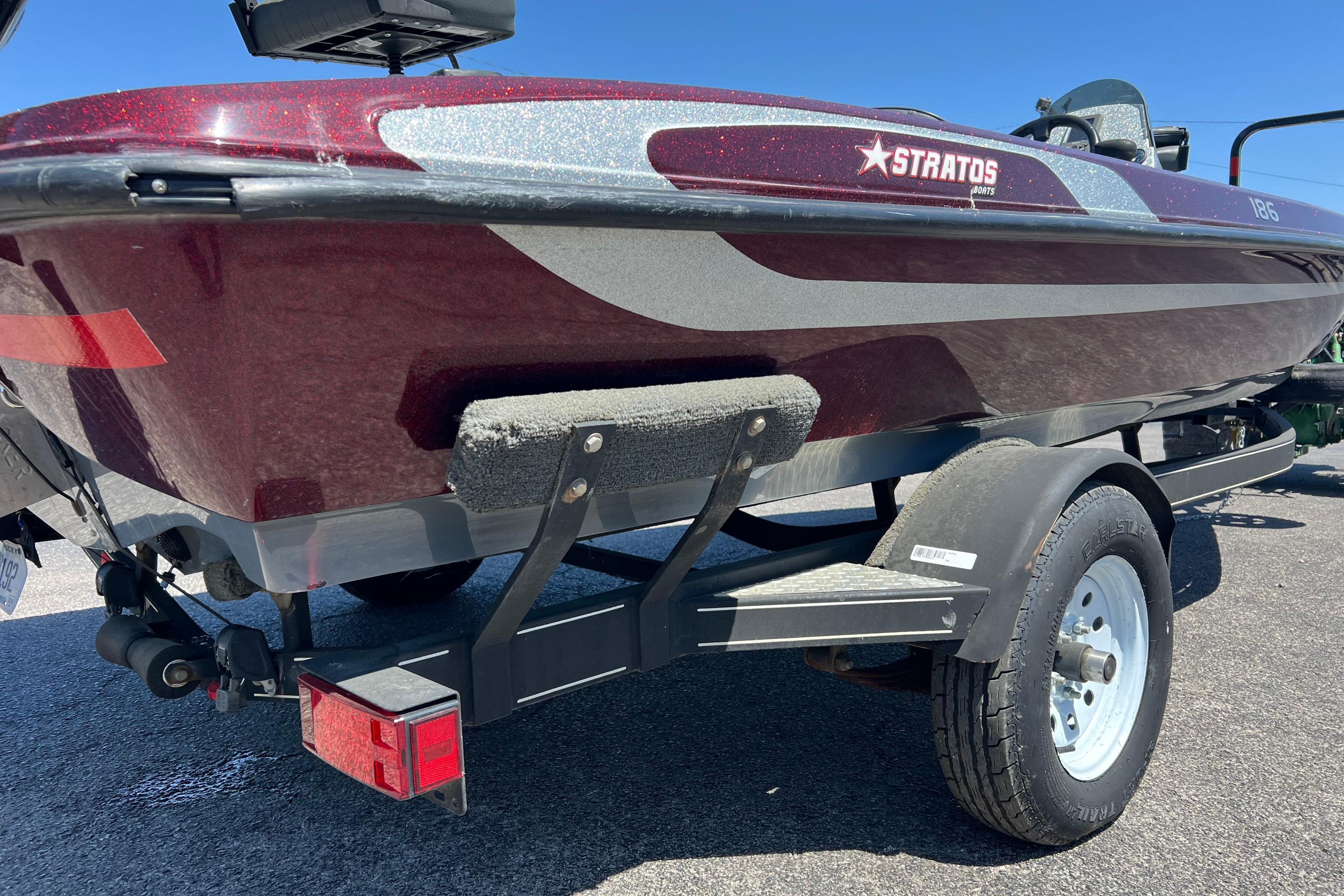 2015 Stratos 186 VLO boat on trailer, maroon and silver design, sunny day.