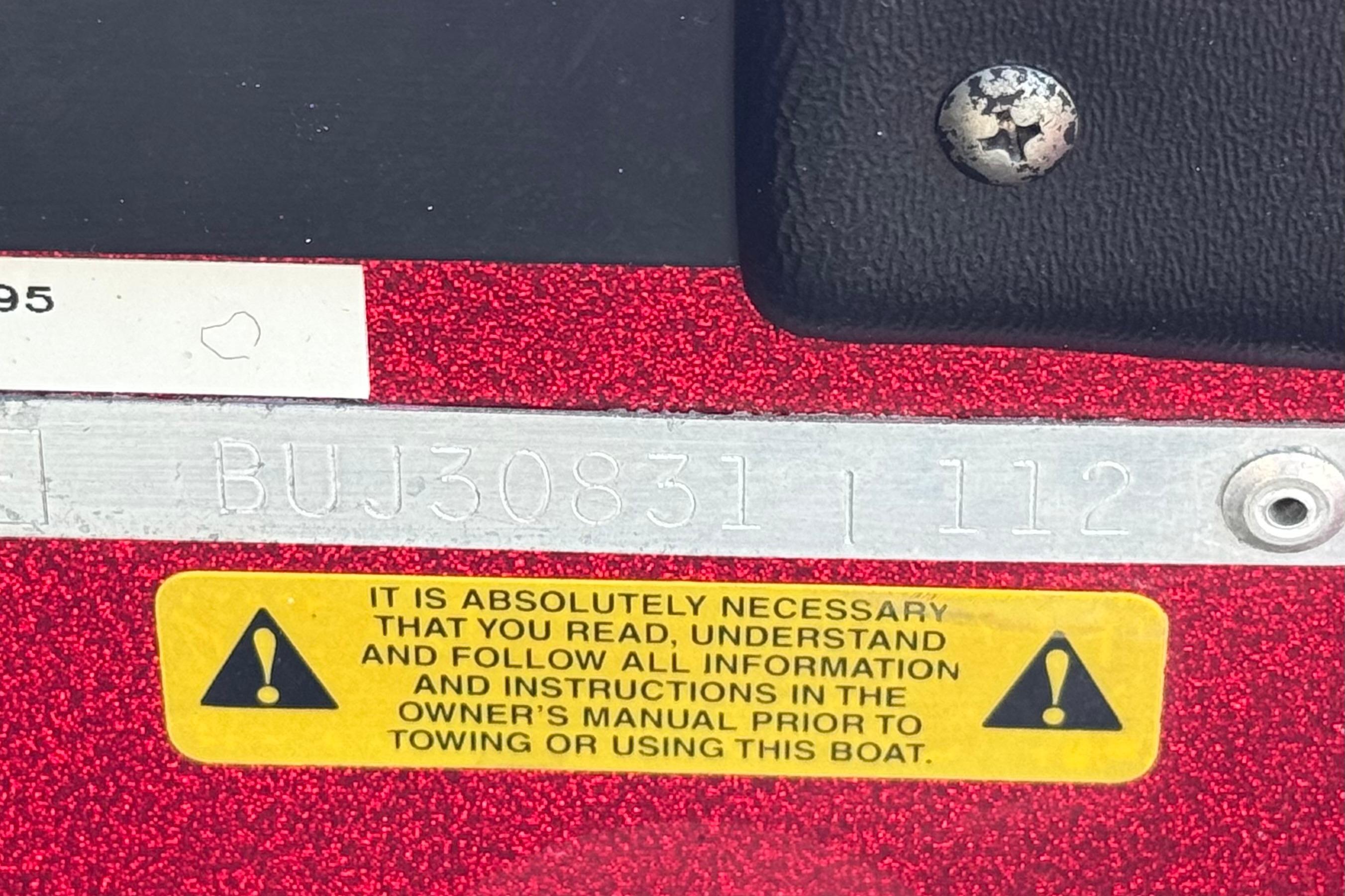 2012 Nitro Z-7 boat warning label and serial number on red surface.