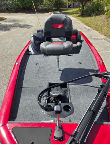 2025 Tracker Pro Team 175 boat with red exterior and gray seating, parked outdoors.