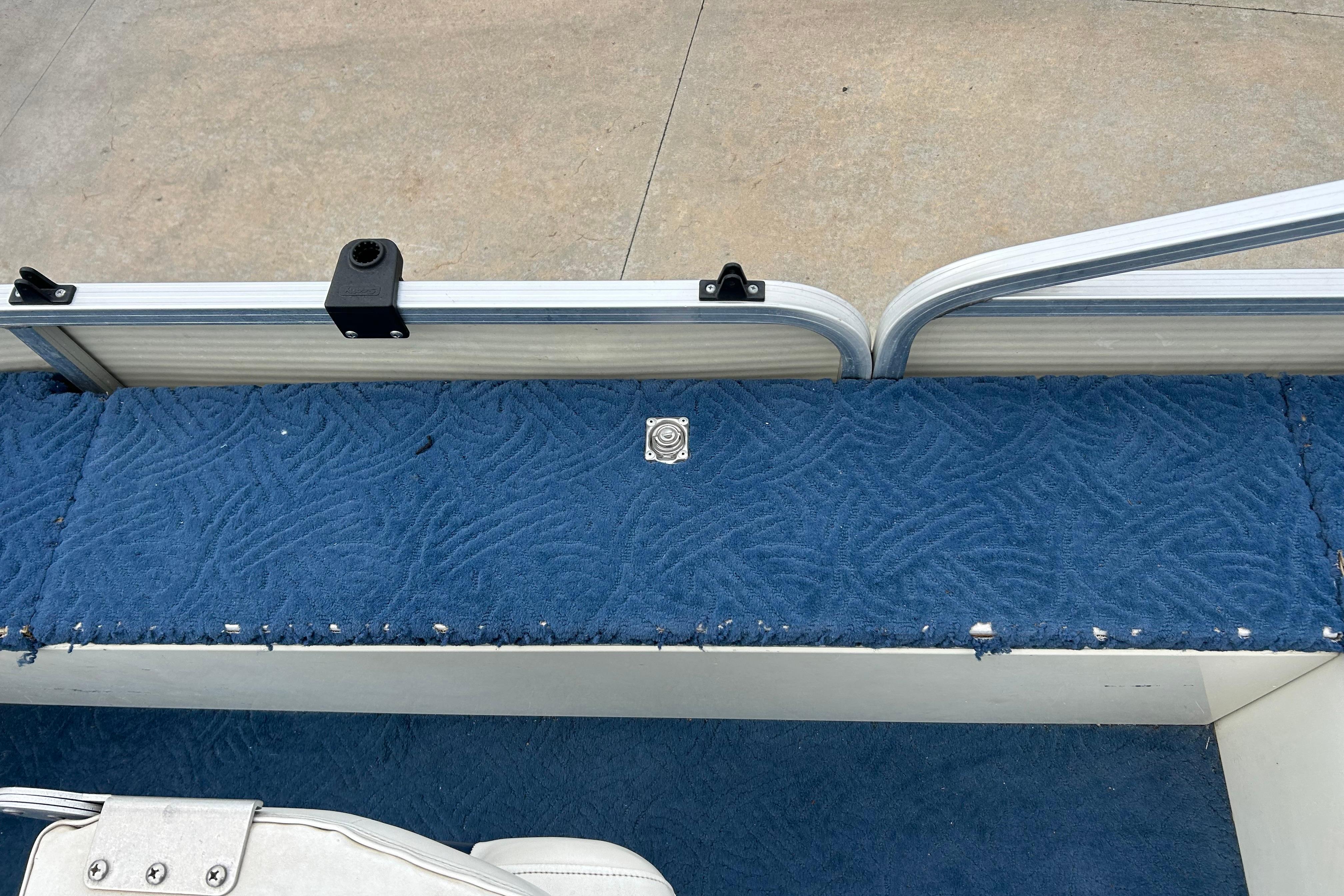 Blue carpeted interior of a 2002 Lowe Trinidad 200 boat, showing seating area.