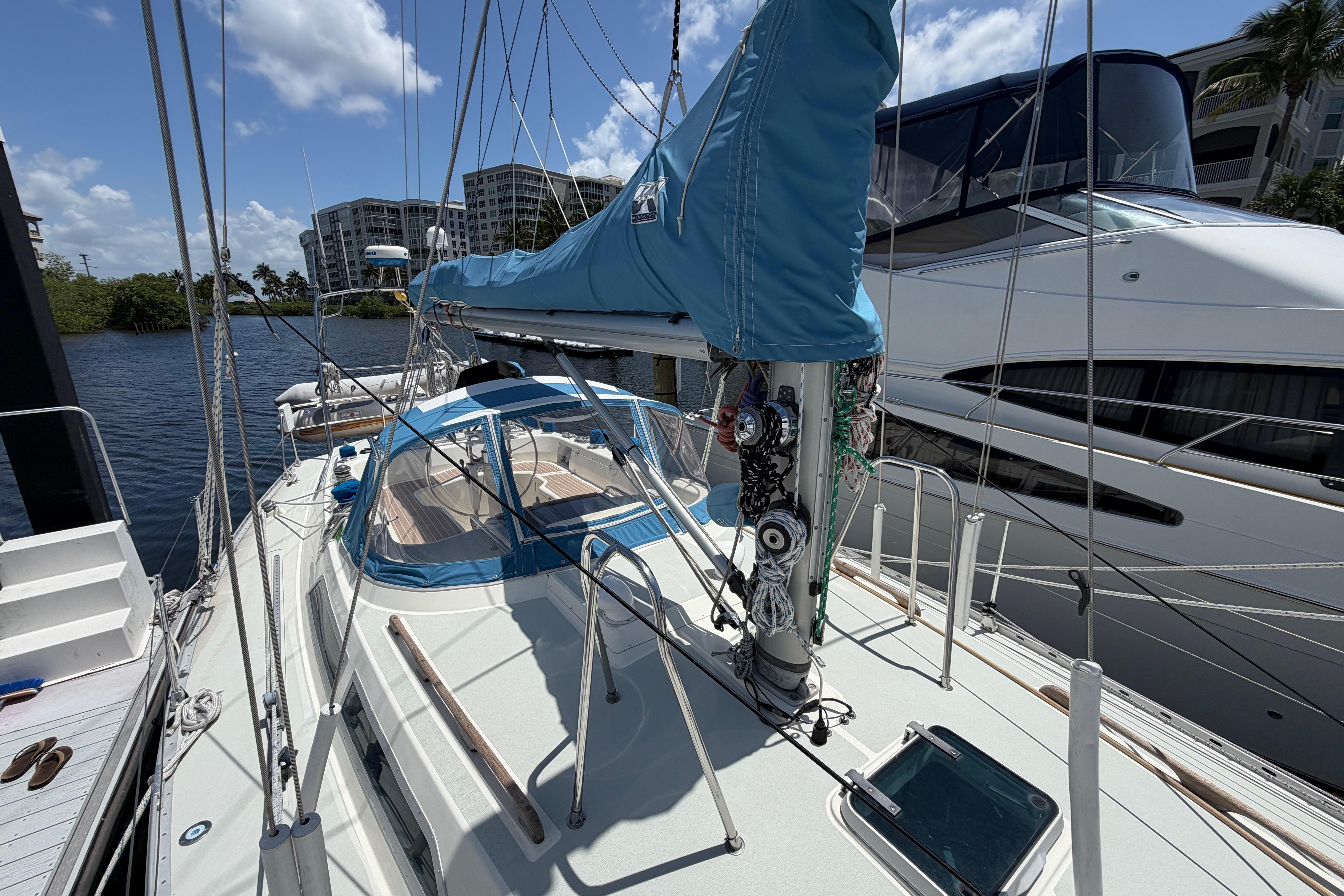 1987 Moody 376 sailboat docked, featuring blue sail cover and spacious deck.