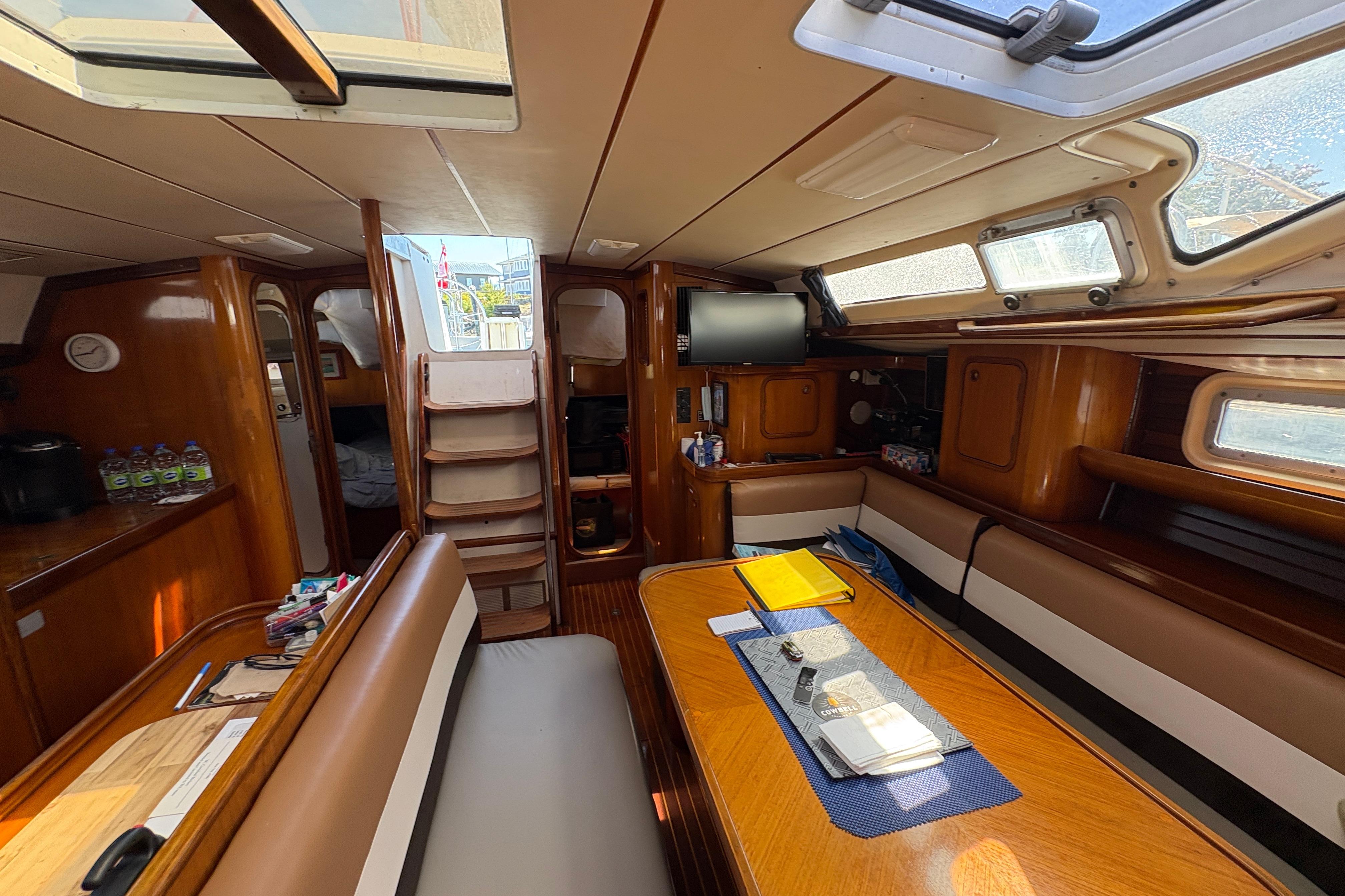 Interior of 1990 Beneteau Oceanis 500 sailboat, featuring wood finishes and seating area.