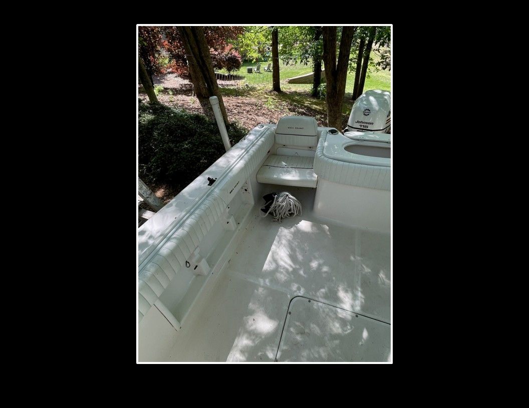2004 Sea Hunt Escape: Spacious deck with seating and storage, surrounded by trees.