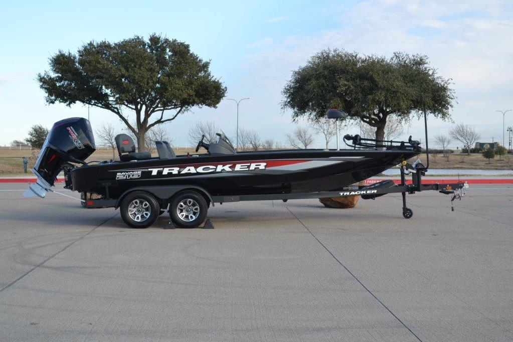 2025 Tracker Savage 215 boat on trailer, parked outdoors with trees in background.