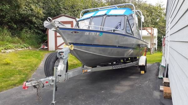 A Hewescraft Sea Runner 210 boat on a trailer in a driveway.