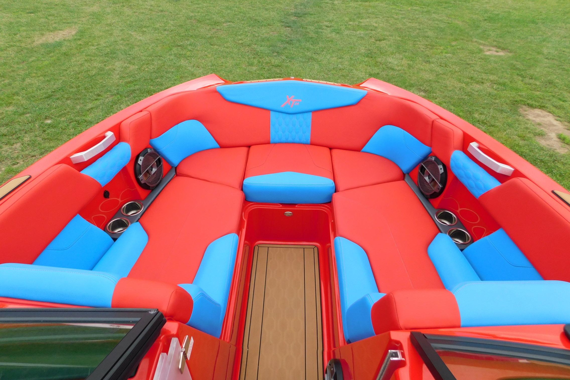 2022 MasterCraft NXT24 boat interior with vibrant red and blue seating, cup holders, and speakers.