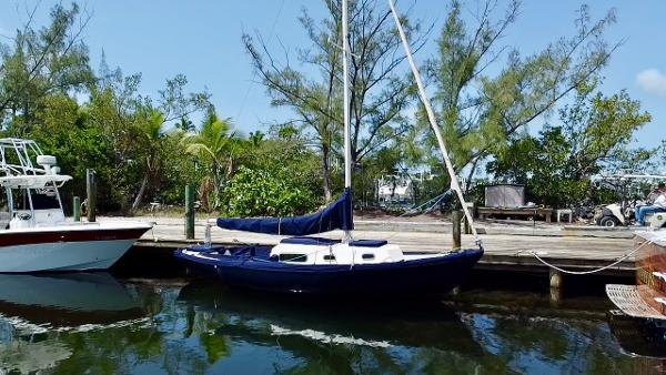 Vintage 1968 Sailboat 24 docked by lush greenery and calm waters.