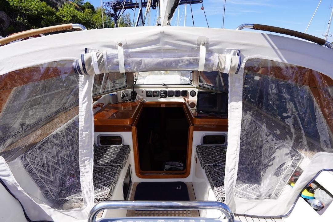 Cockpit view of 2015 Hallberg-Rassy 55 sailboat with protective canopy and seating.