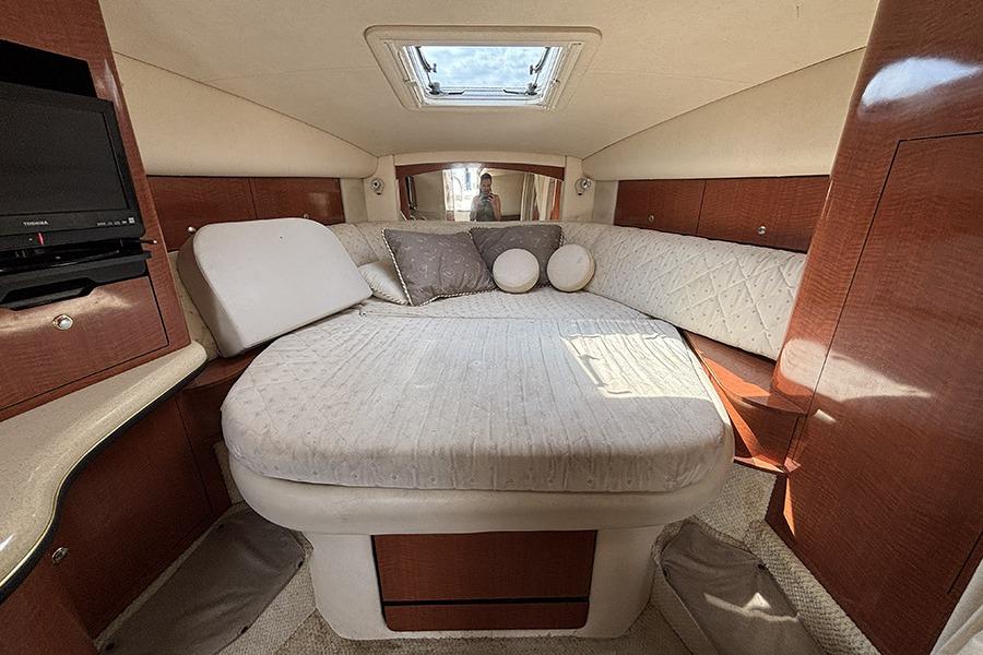 Interior cabin of 2002 Sea Ray Sundancer 320 with cozy bed and TV.