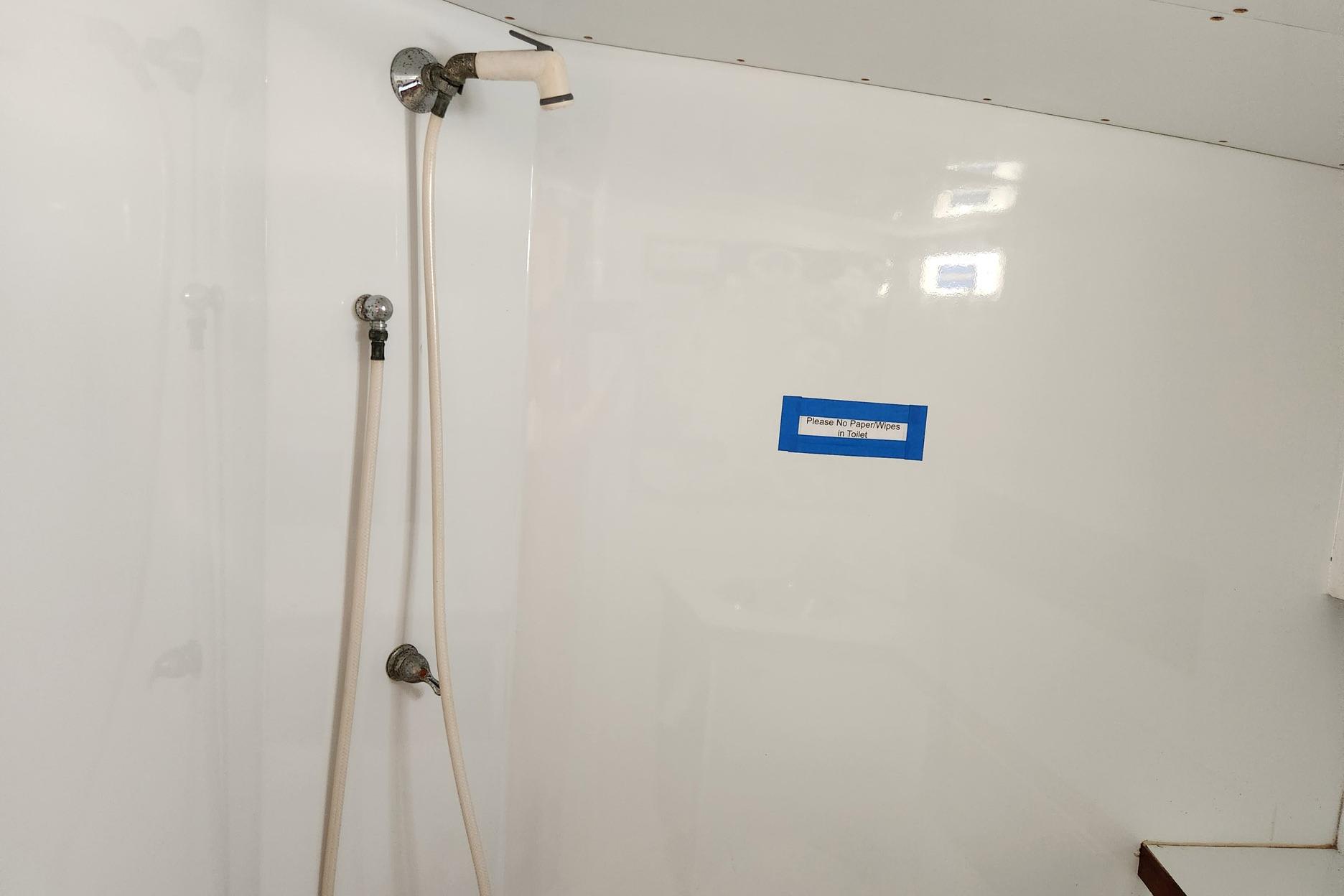 Shower area in 1987 Young Brothers Custom Sport Fish boat with caution sign.