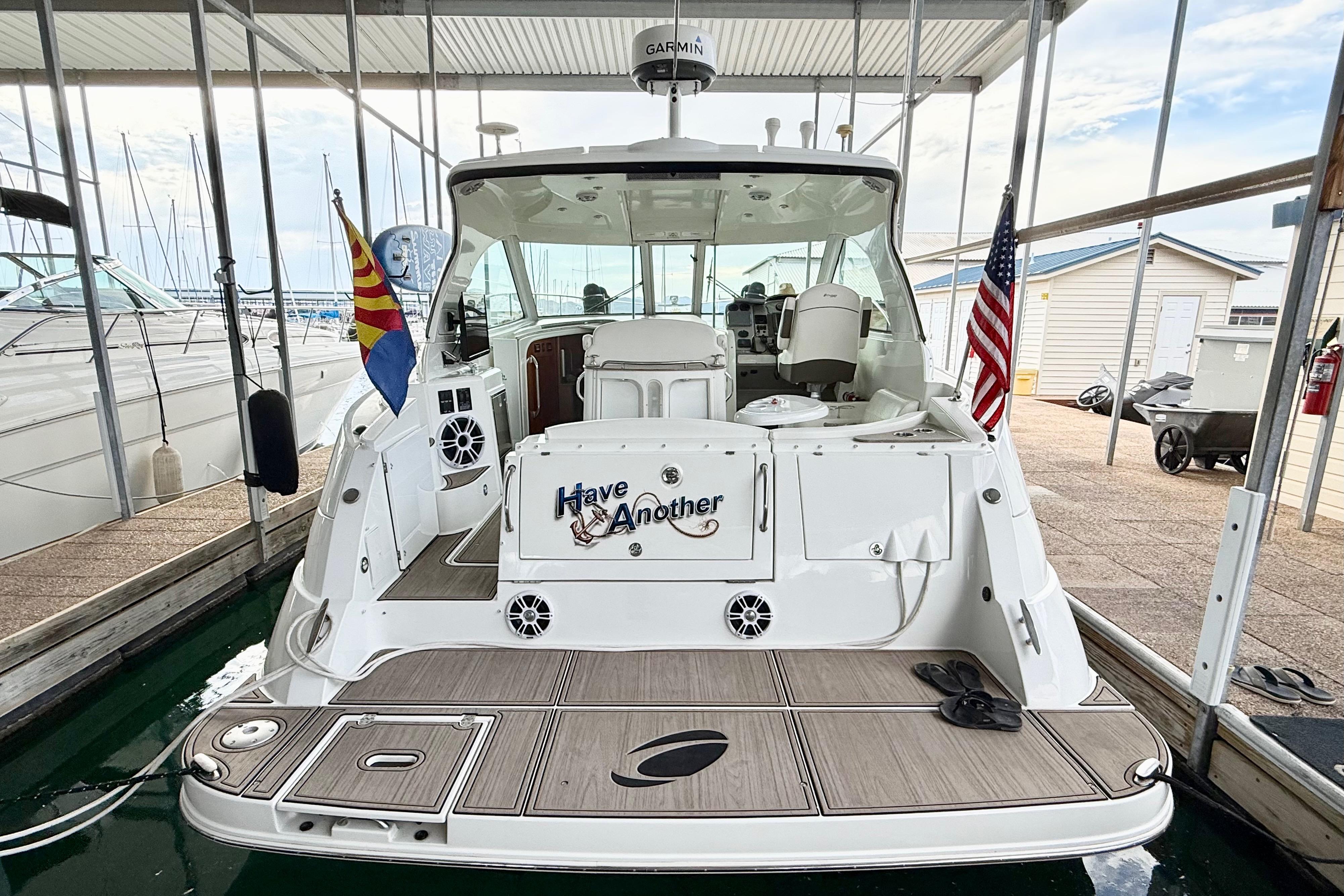 2011 Cruisers Yachts 390 Sports Coupe docked, featuring flags and spacious deck area.