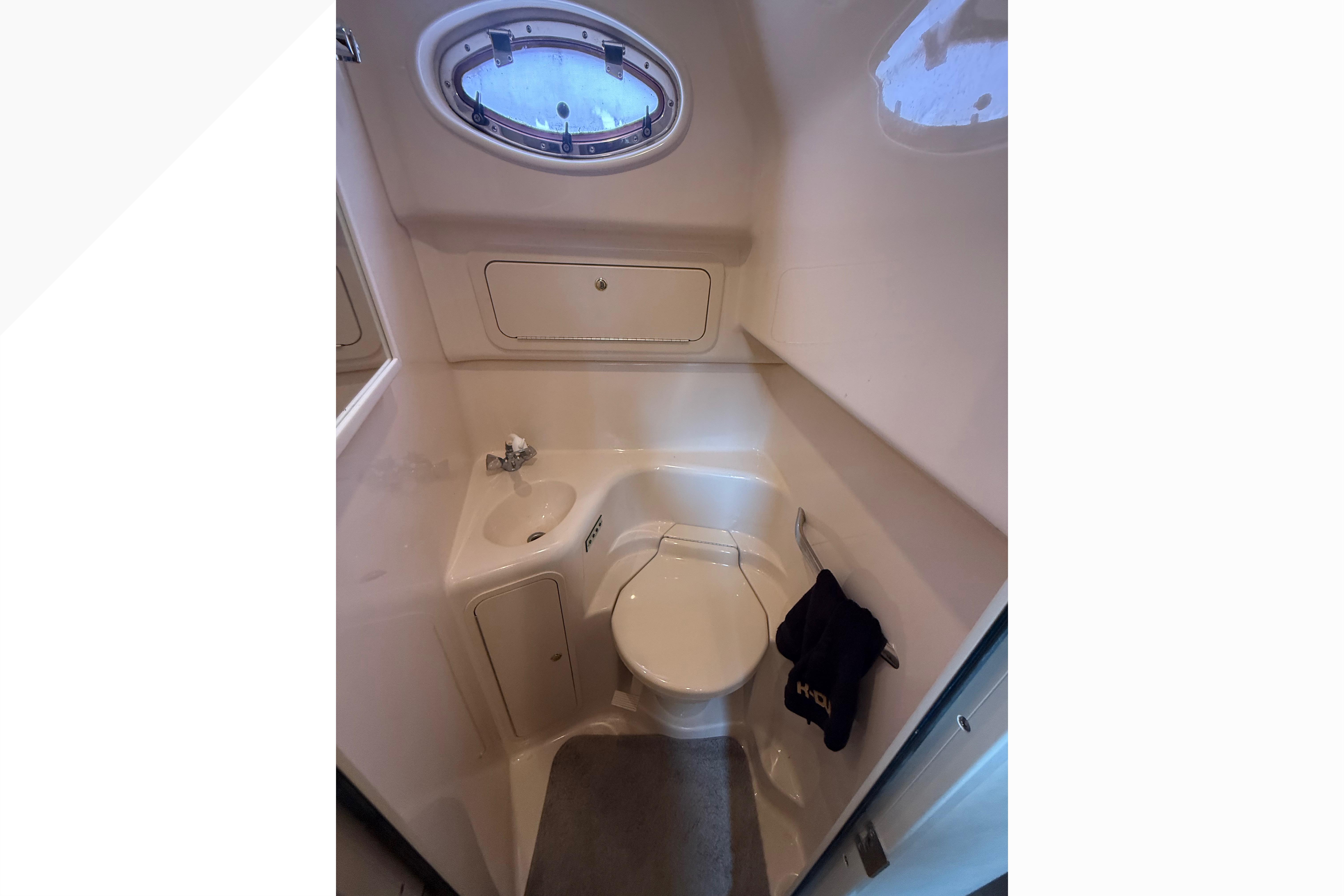 1998 Sea Ray Sundancer 400 yacht bathroom with sink, toilet, and porthole window.
