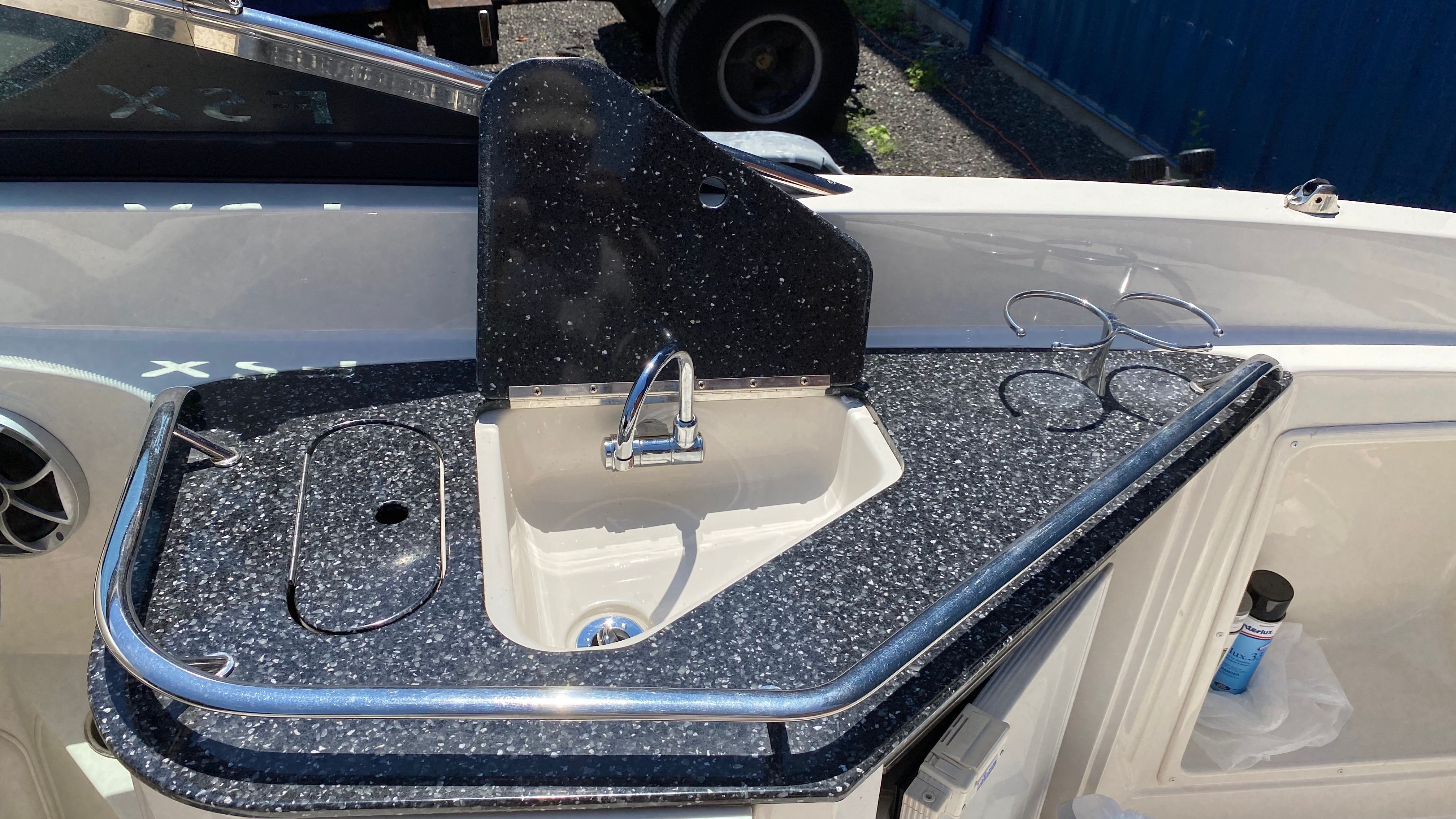 A sink on a boat with a black speckled countertop and holders.