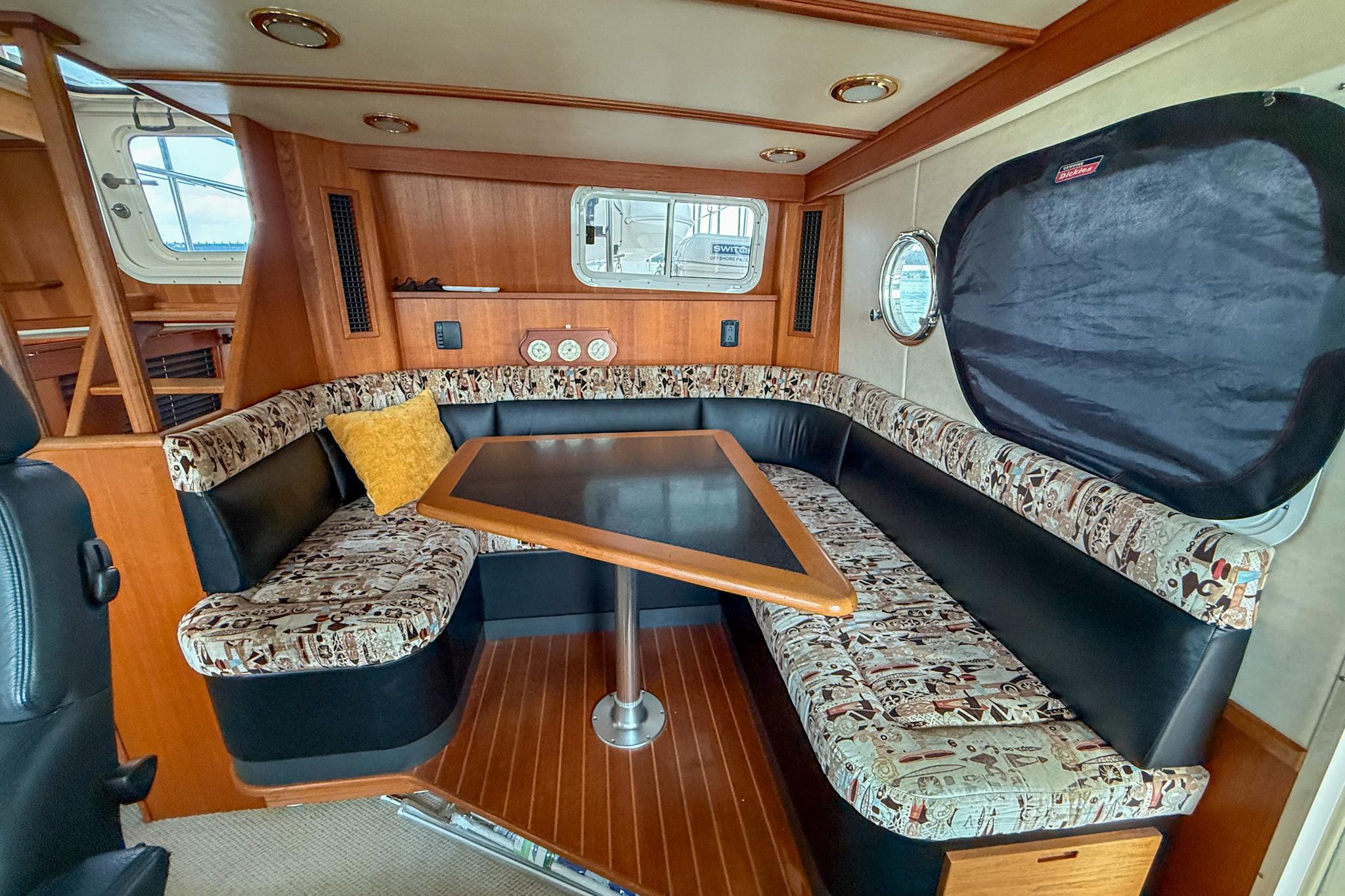 Cozy dining area in a 2007 Nordic Tug 54 with patterned seating and wooden table.