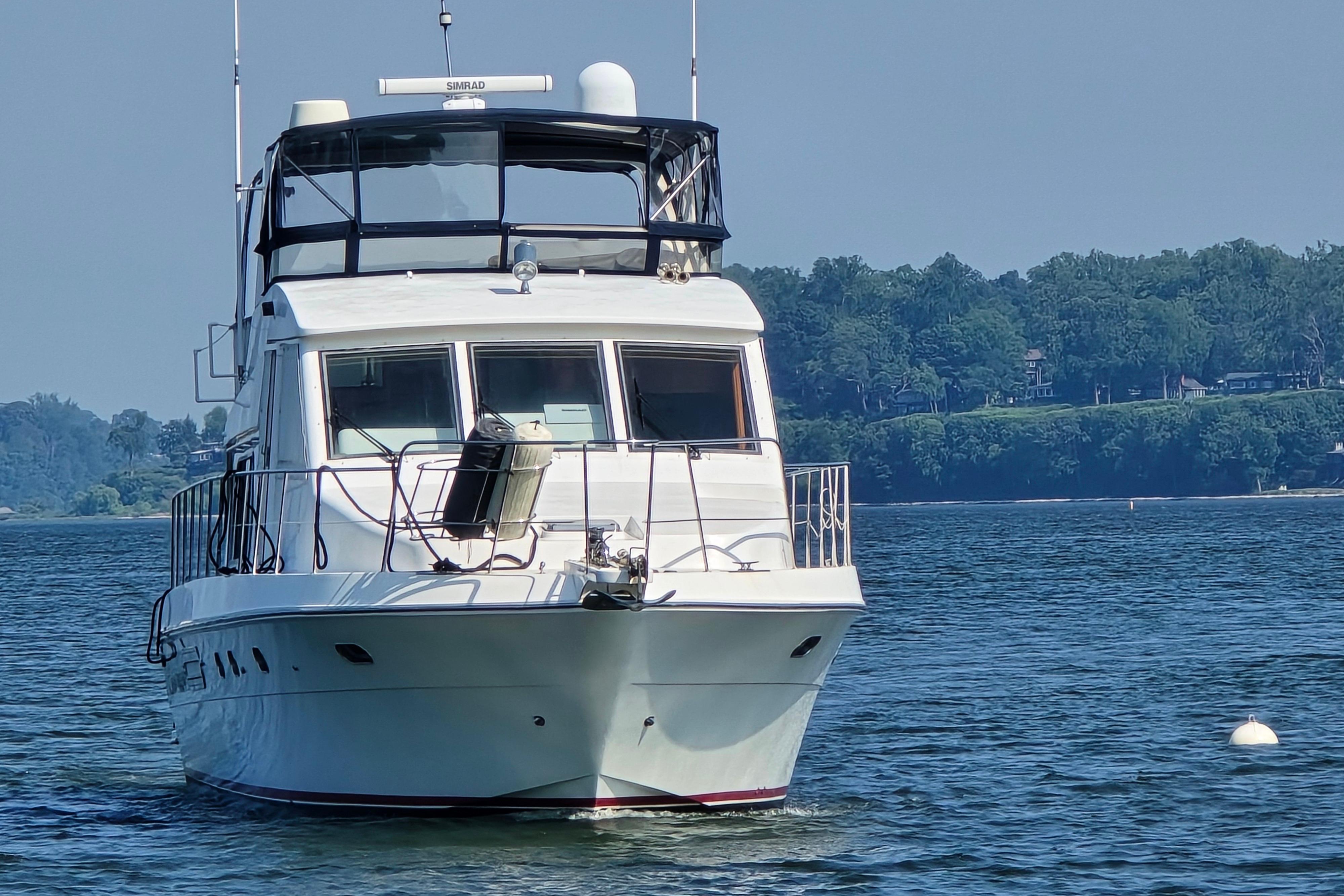 2004 Grand Harbour 58 yacht on calm water with scenic forested shoreline.
