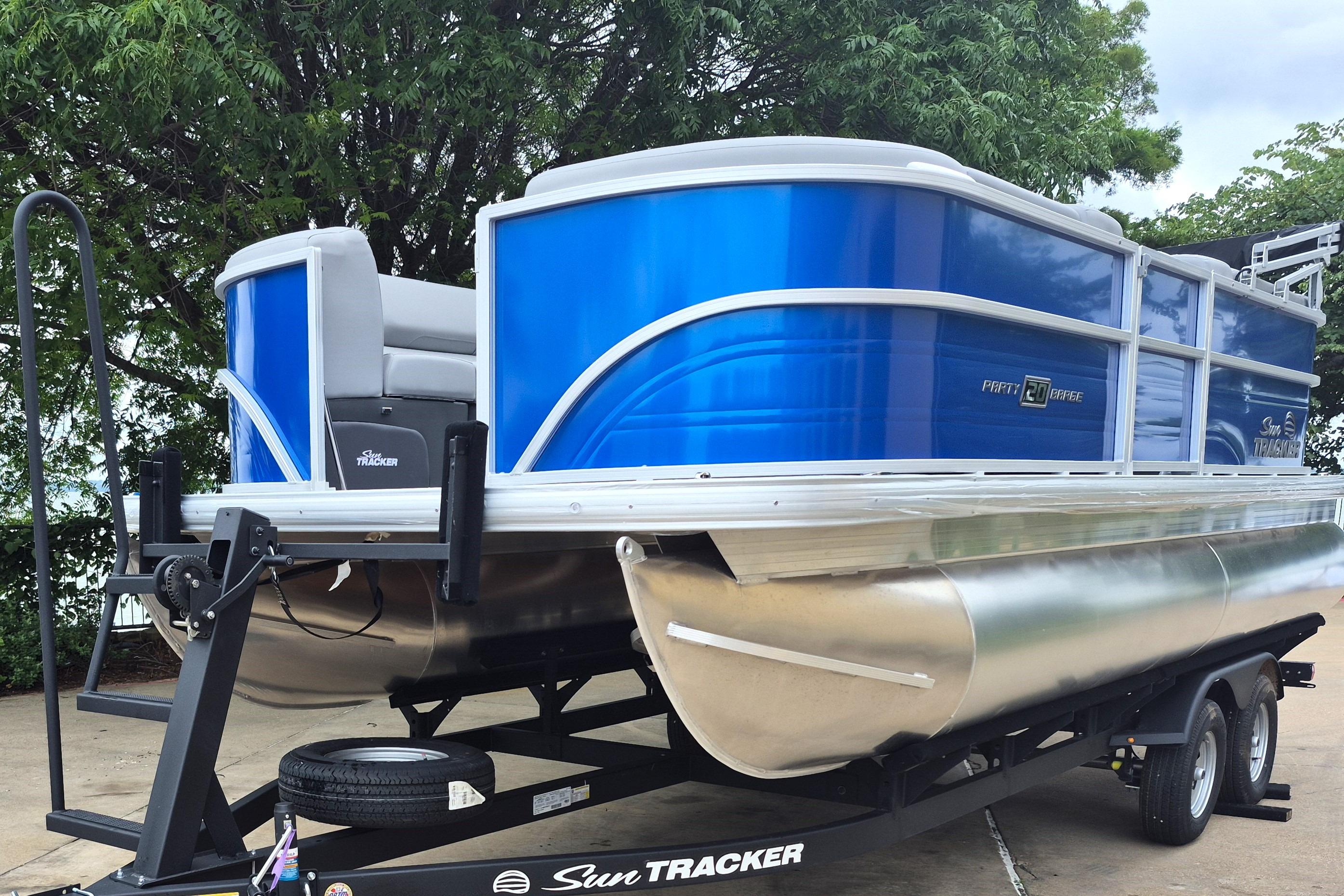 2026 Sun Tracker Party Barge 20 DLX pontoon boat on trailer, vibrant blue exterior.