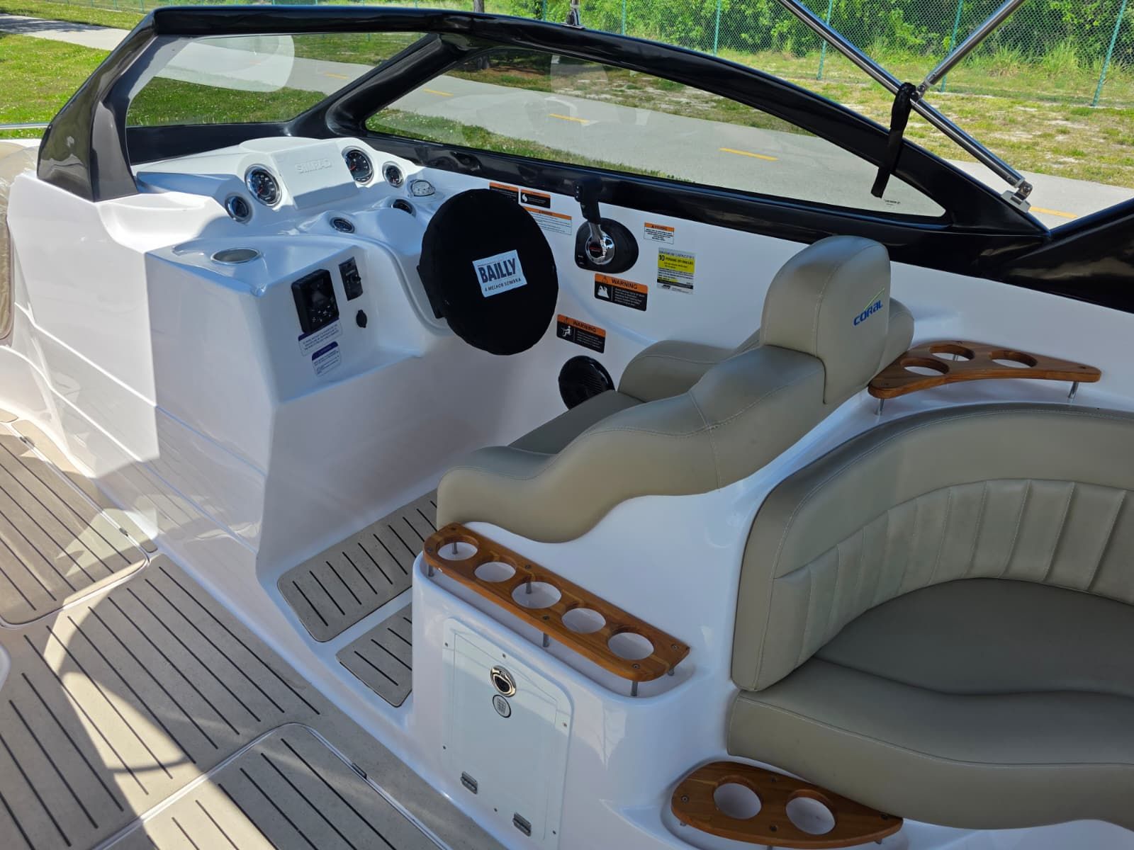 The image shows the cockpit of a Coral 26 boat with beige seats and wood accents.