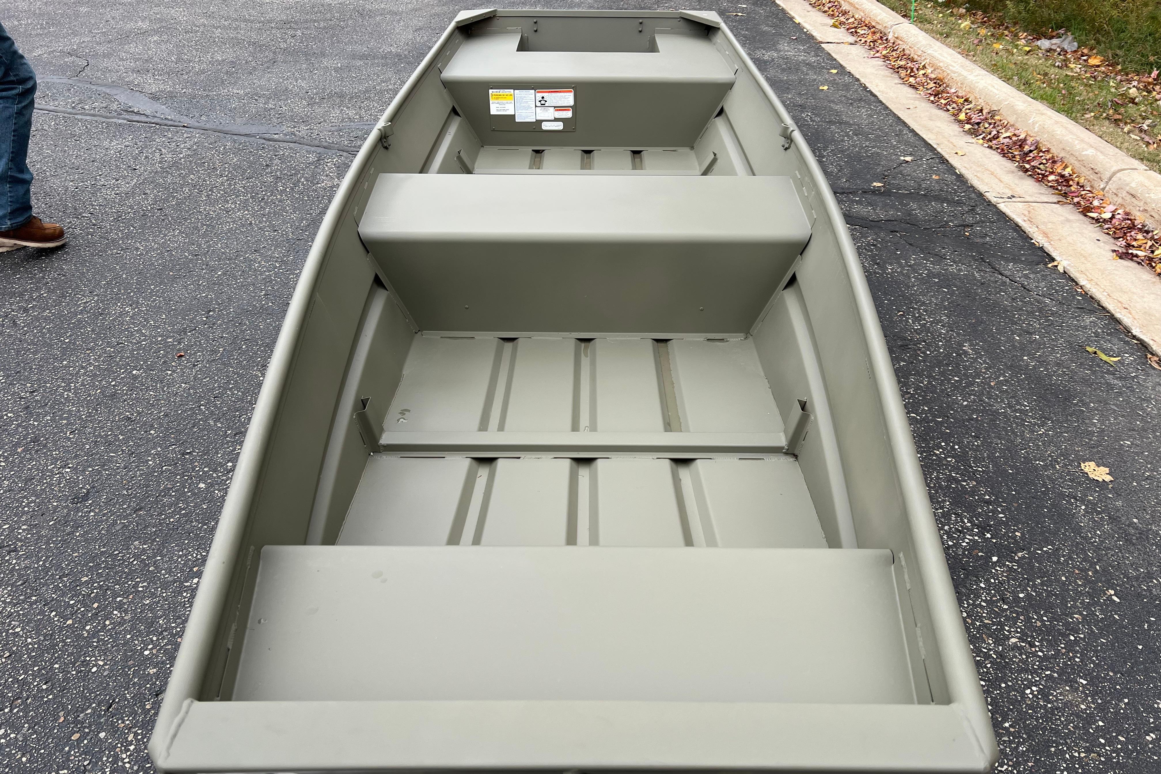2026 Tracker Grizzly 14 Jon boat on pavement, showcasing interior seating and storage.