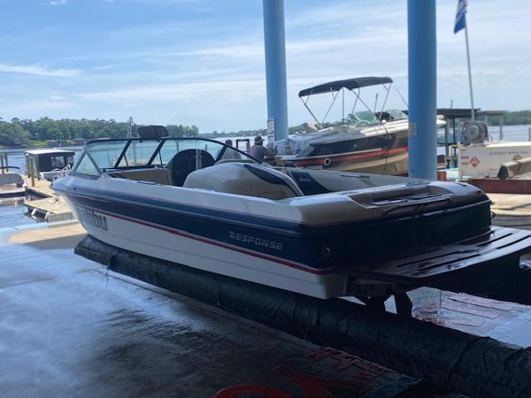 1998 Malibu Response boat on lift at marina, with other boats in background.
