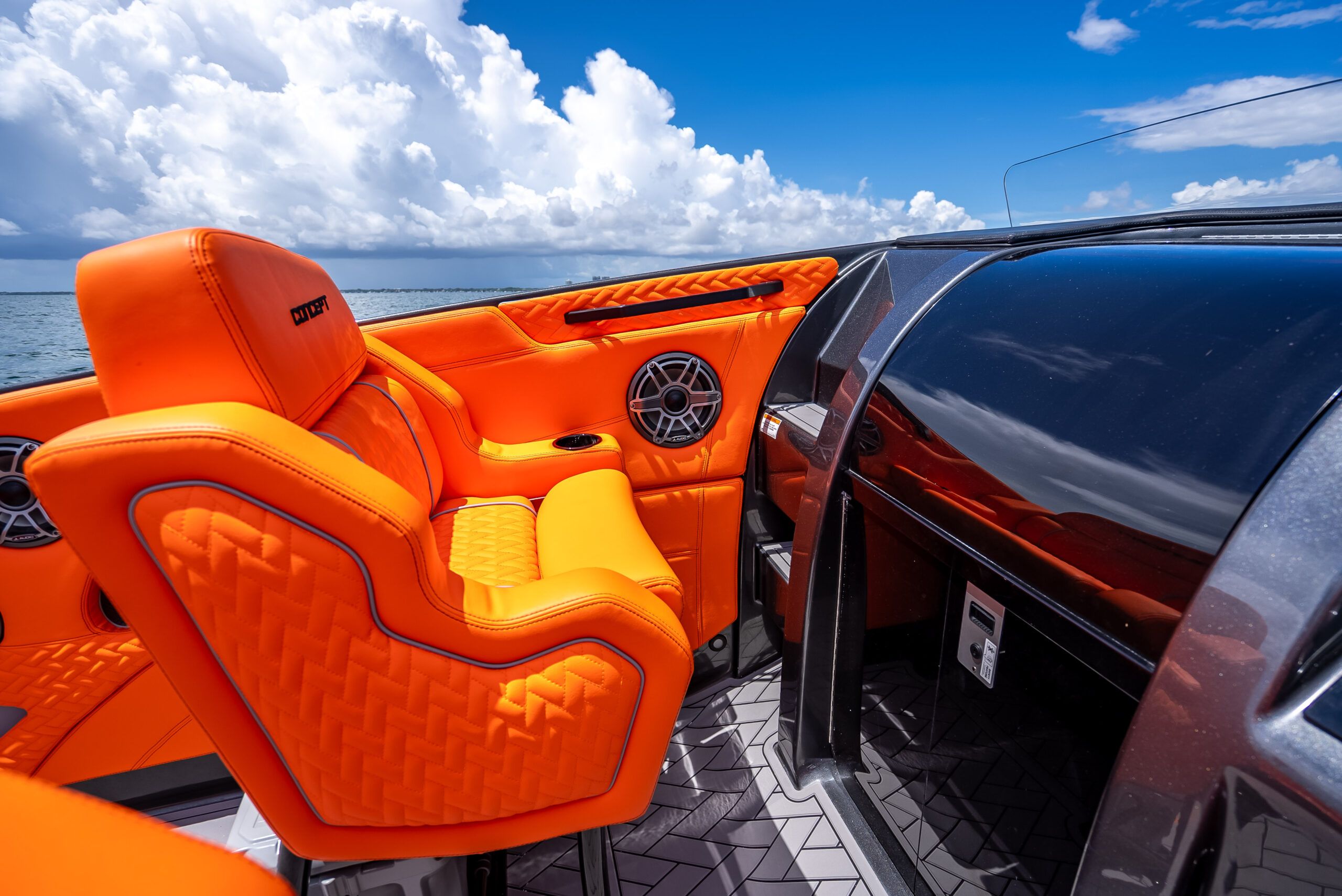 The image shows a modern boat interior with bright orange seats and a glossy dashboard.