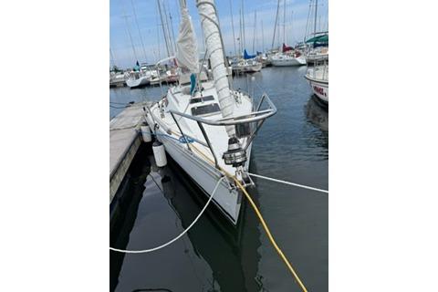 1986 Beneteau First 305 sailboat docked in a marina, surrounded by other boats.