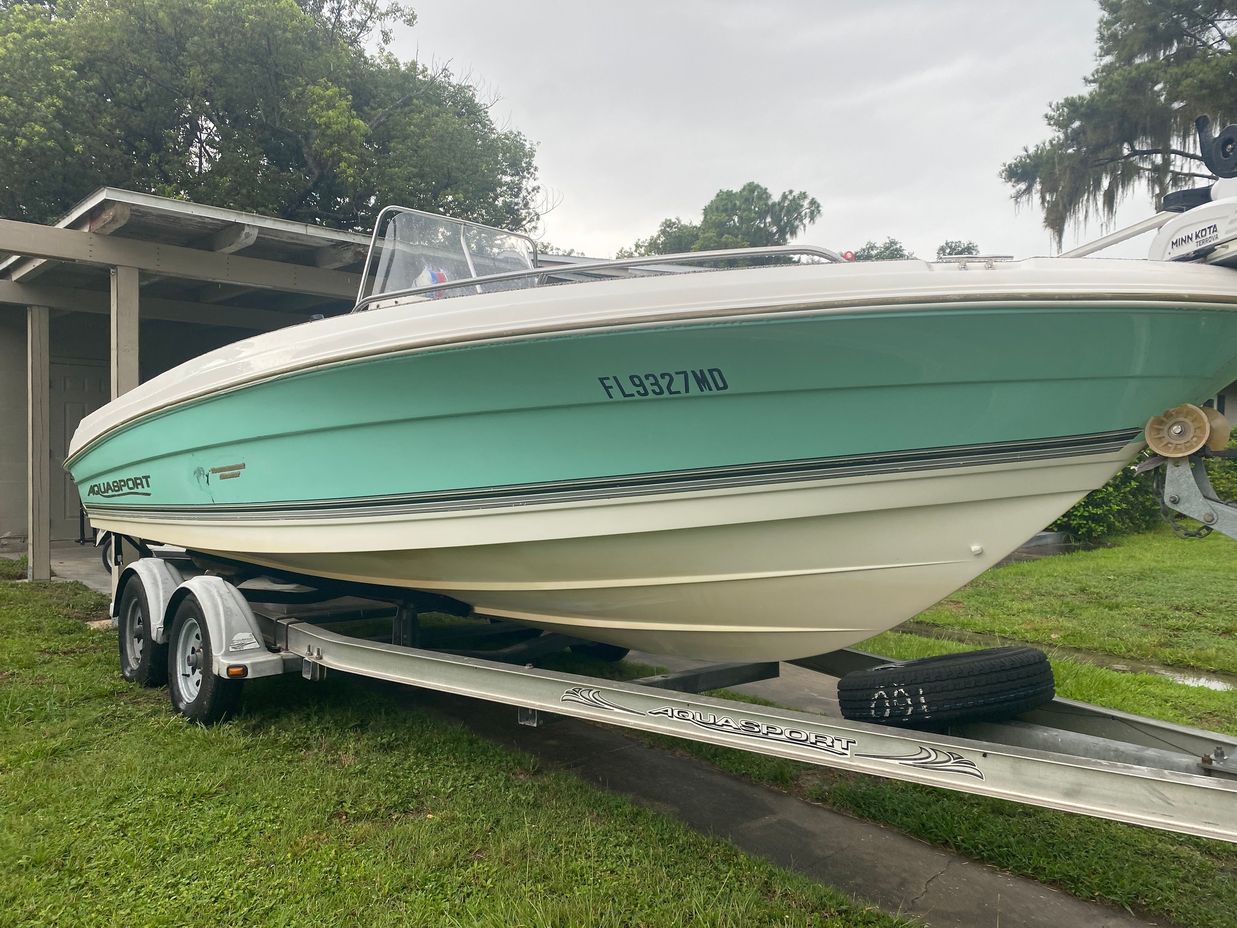 A 2003 Aquasport 201 Osprey boat parked on a trailer outdoors.