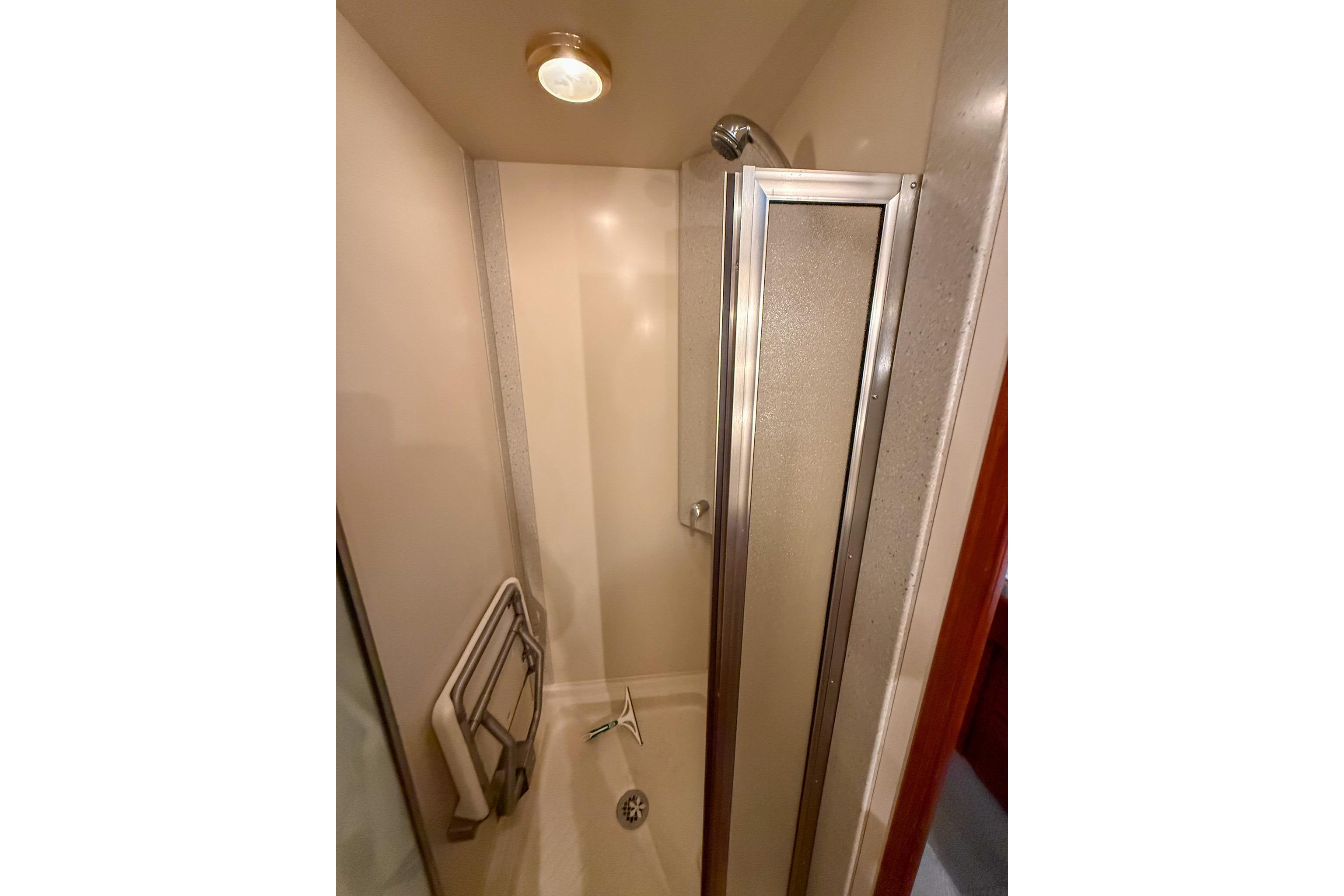 Shower area in 2007 Nordic Tug 54 yacht with glass door and grab bar.