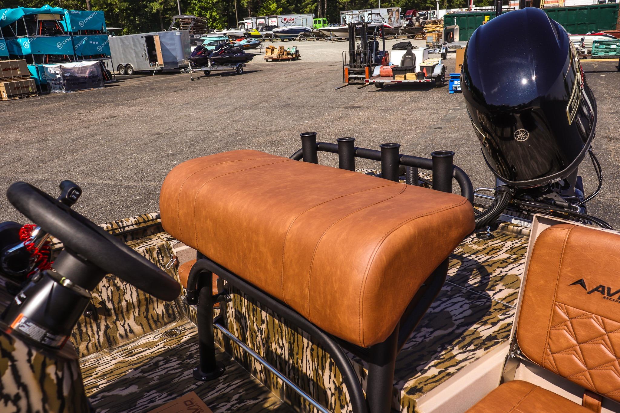 Avid 20 Rogue CC 2027: A boat with brown upholstery and an outboard motor in a parking area.