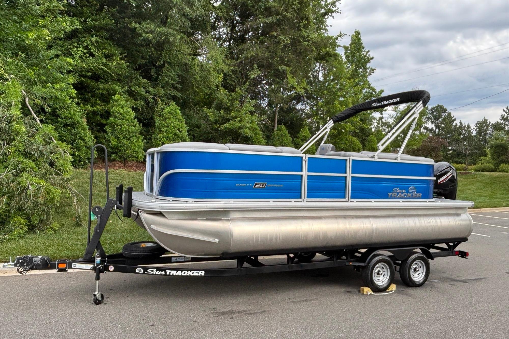 2026 Sun Tracker Party Barge 20 DLX pontoon boat on trailer, parked outdoors.