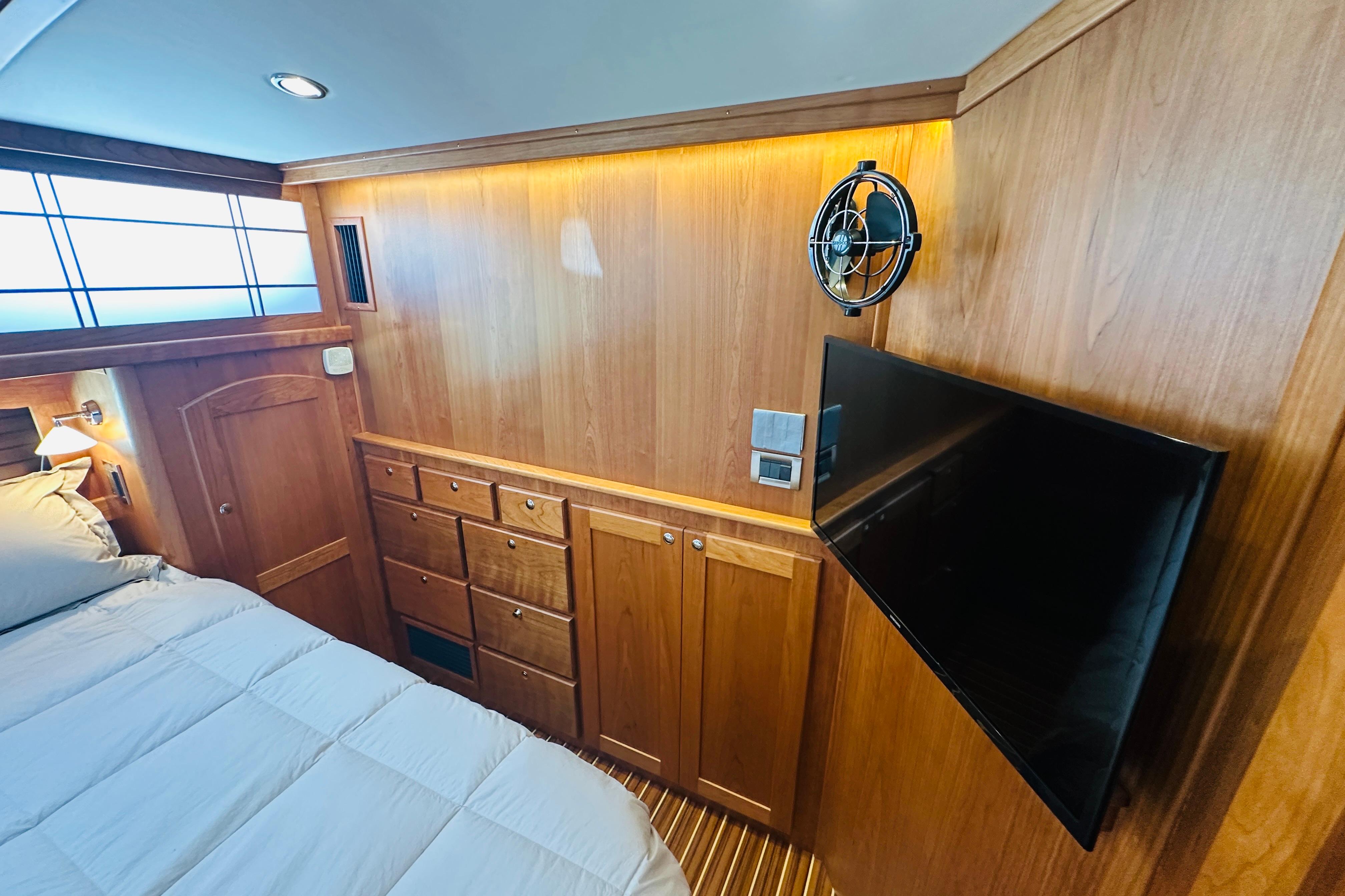 Bedroom interior of 2025 Sabre 48 Salon Express yacht with wood paneling and mounted TV.