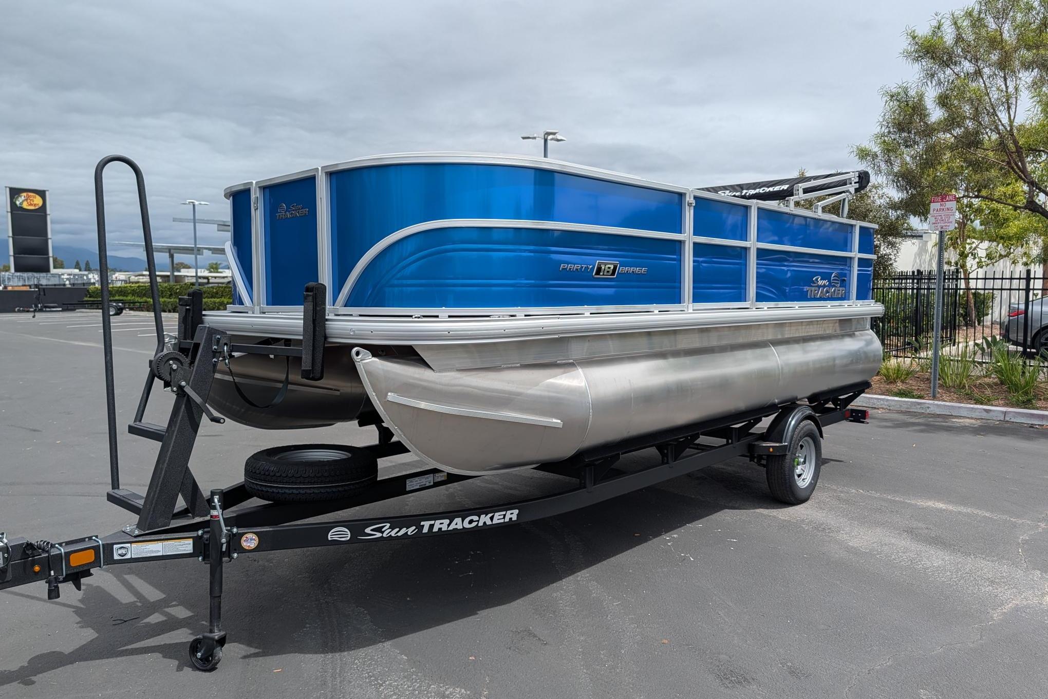 2026 Sun Tracker Party Barge 18 DLX pontoon boat on trailer in parking lot.
