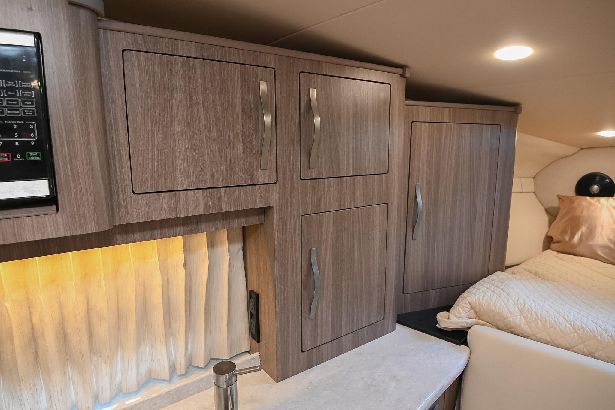 Interior of 2021 Regal 33 Express yacht with wood cabinets and cozy bedding.