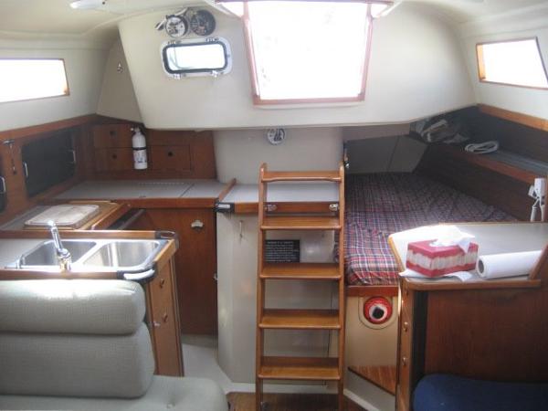 Interior of a C&C Landfall yacht with kitchen, bed, and wooden ladder.