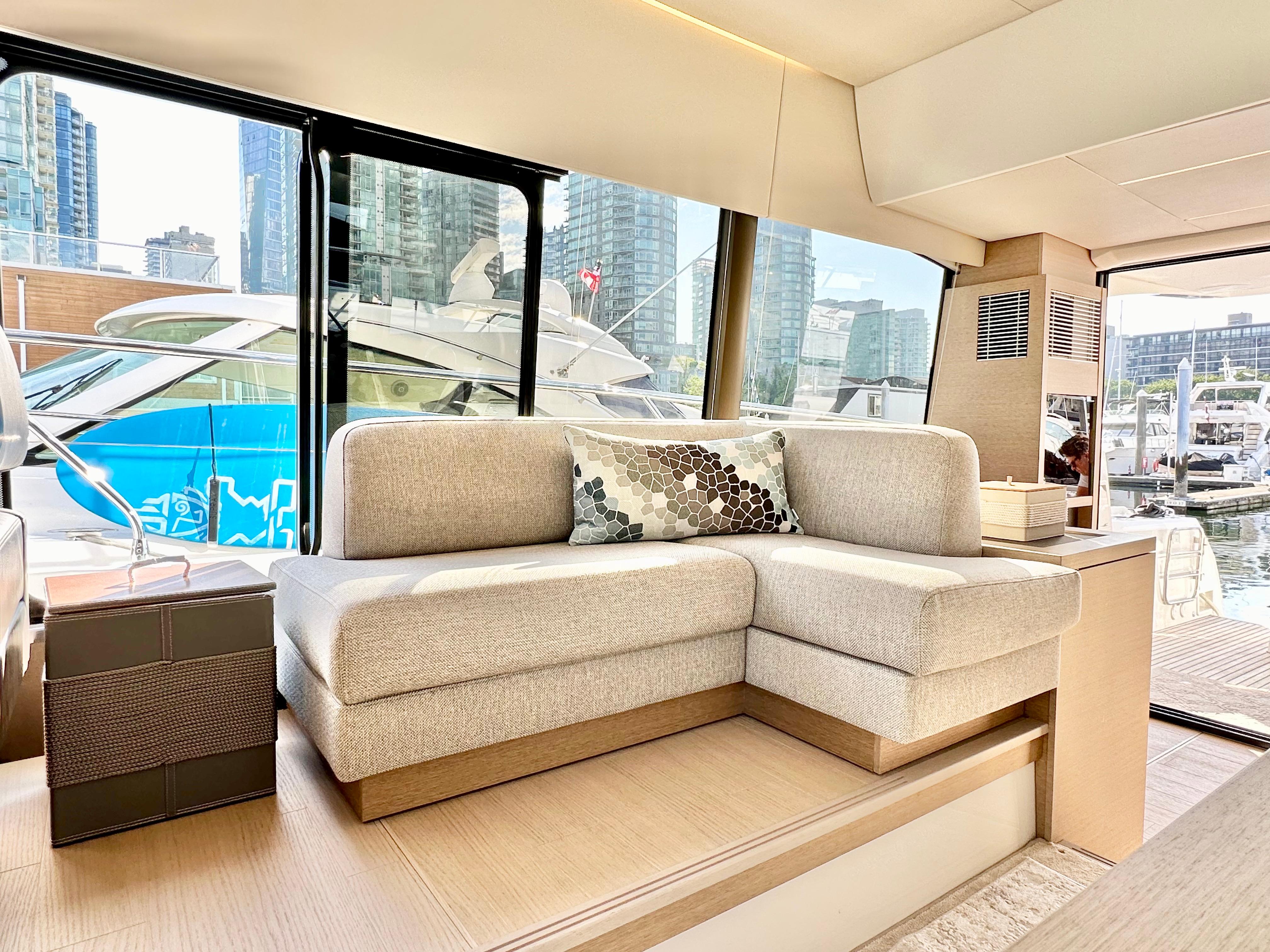 Luxurious interior of 2023 Prestige 520 yacht with modern sofa and marina view.