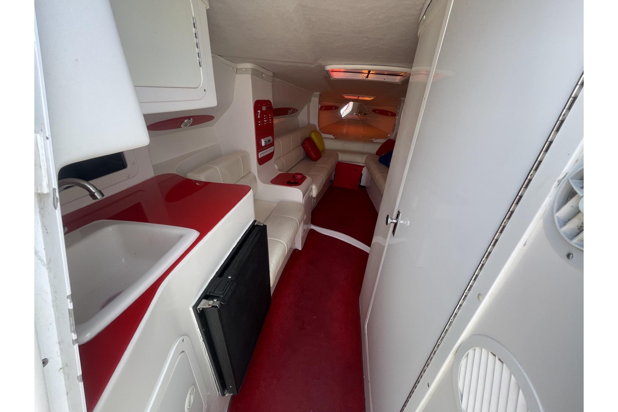 Interior of a 2006 Sonic 386 boat with red and white seating and kitchenette.