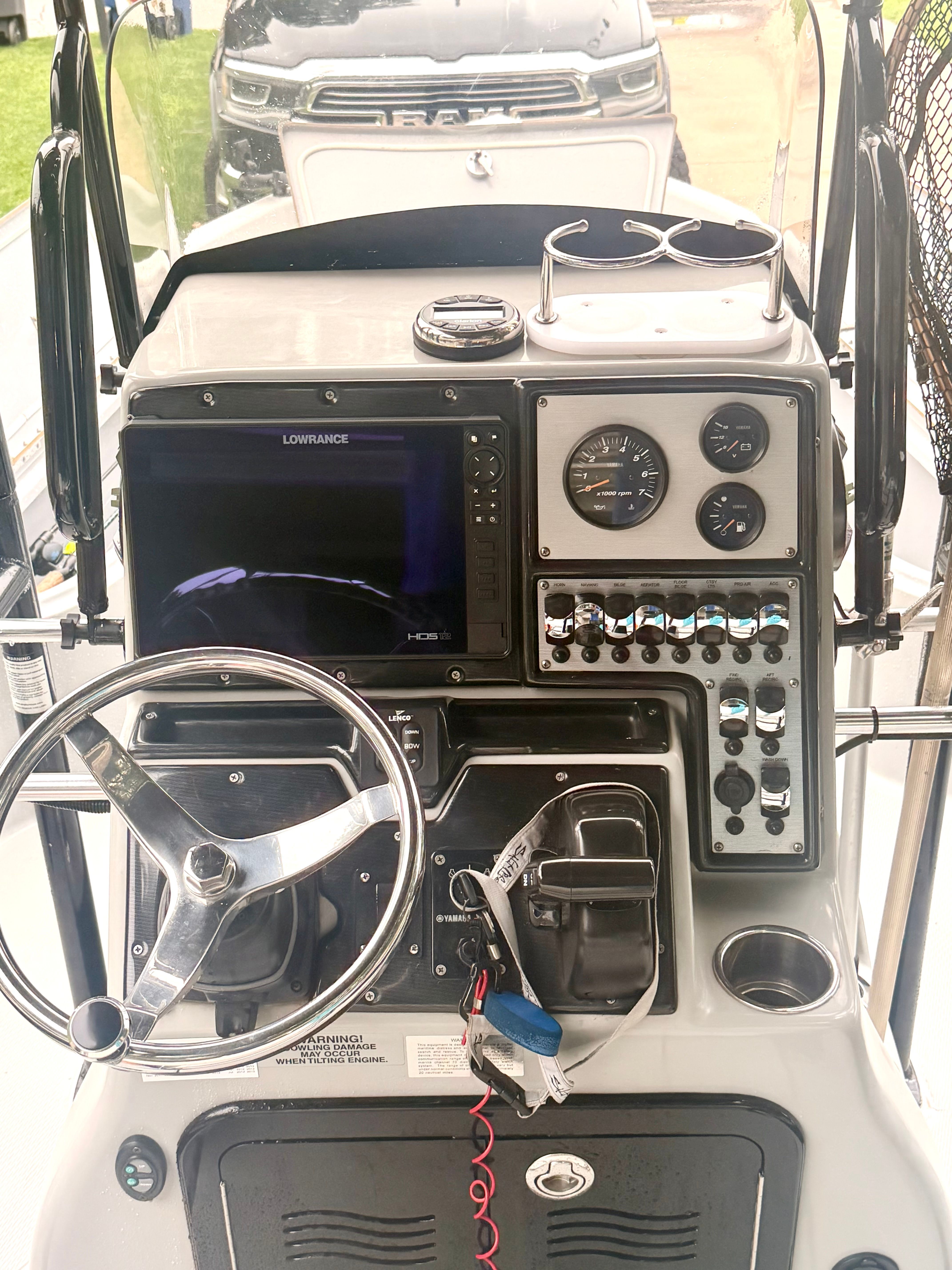 The image shows a boat's helm with a steering wheel, instruments, and a screen.