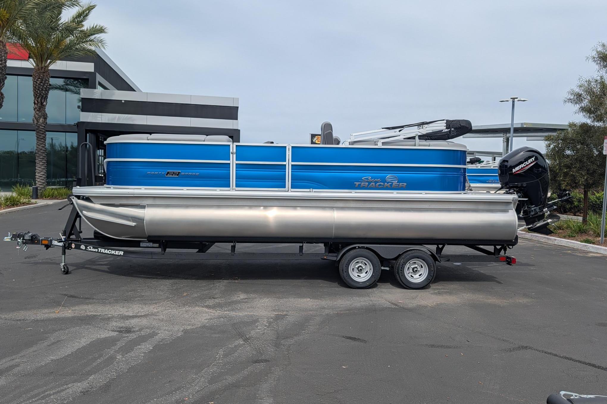 2026 Sun Tracker Party Barge 22 DLX pontoon boat on trailer, parked outdoors.