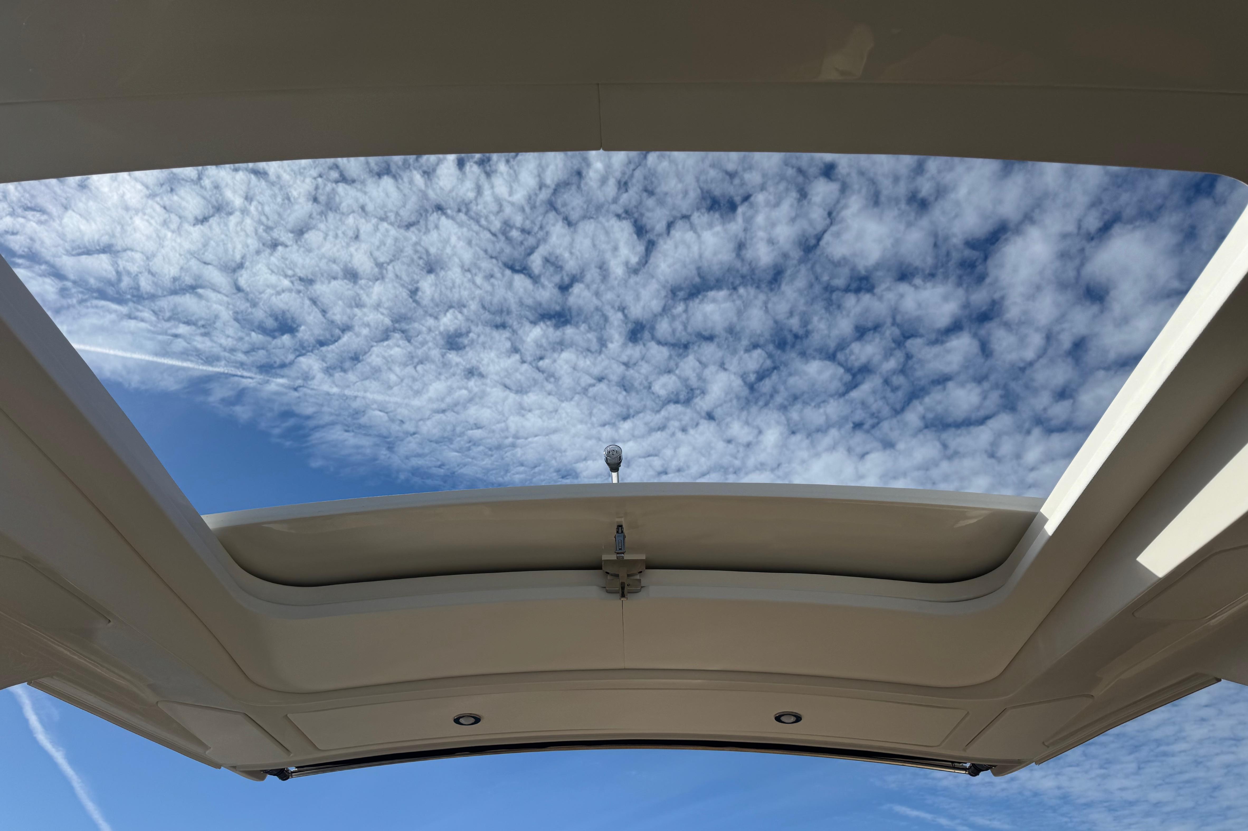 2026 Sea Ray SLX 310 boat with open sunroof under a cloudy sky.