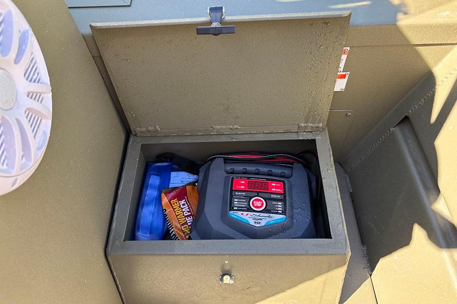 Storage compartment in 2022 Lowe Roughneck 1660 boat with battery charger and accessories.