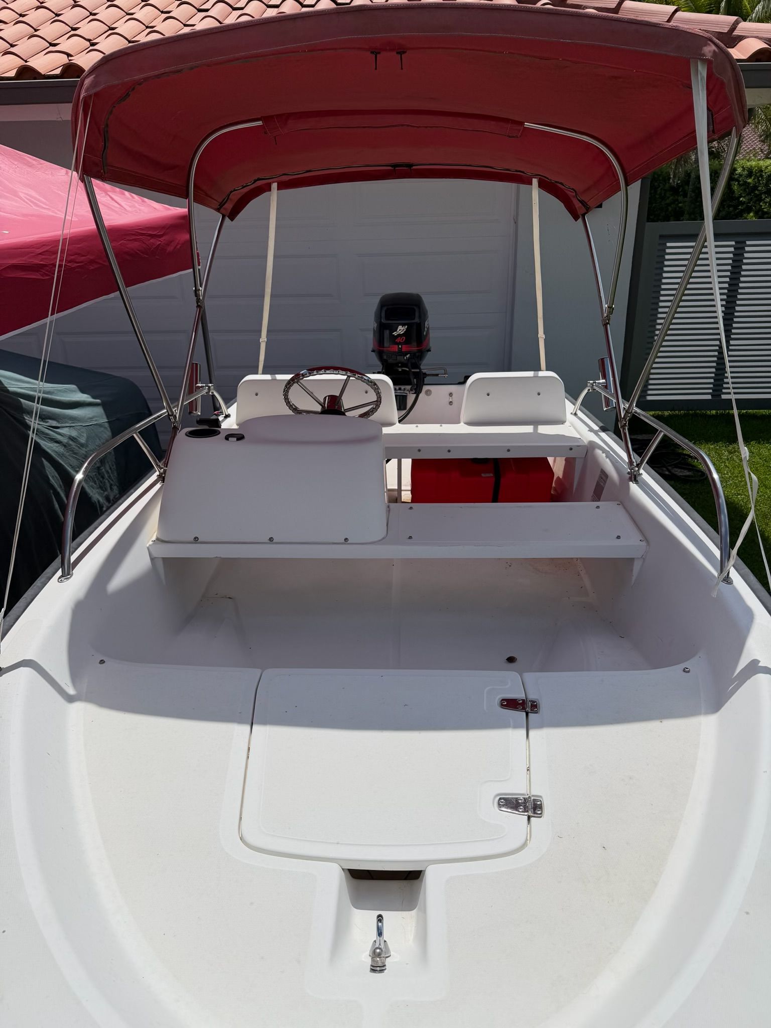 A 2003 Boston Whaler 130S with a red sunshade and white interior.