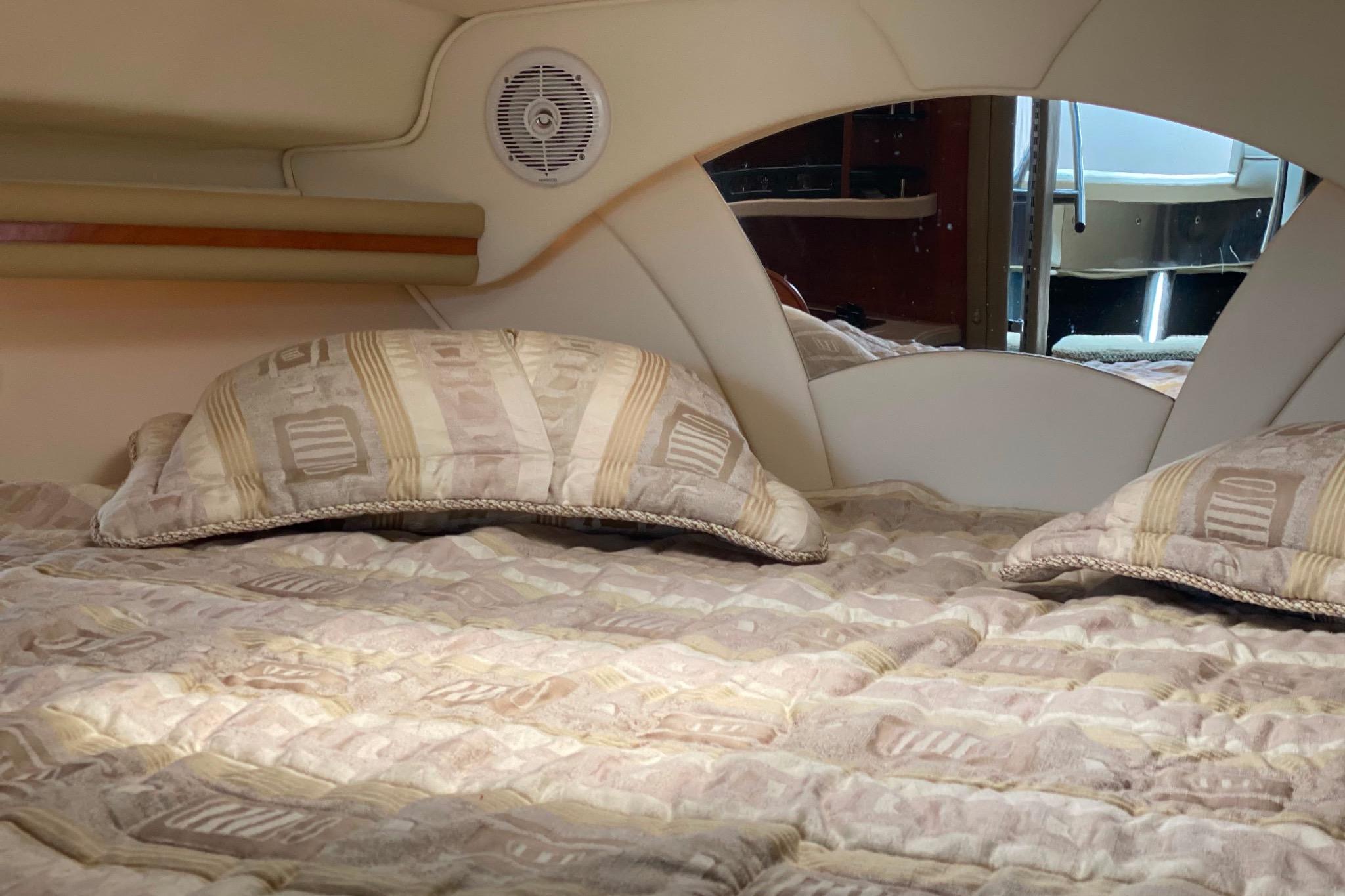 Interior cabin of 2003 Rinker Fiesta Vee 342 with cozy bedding and pillows.