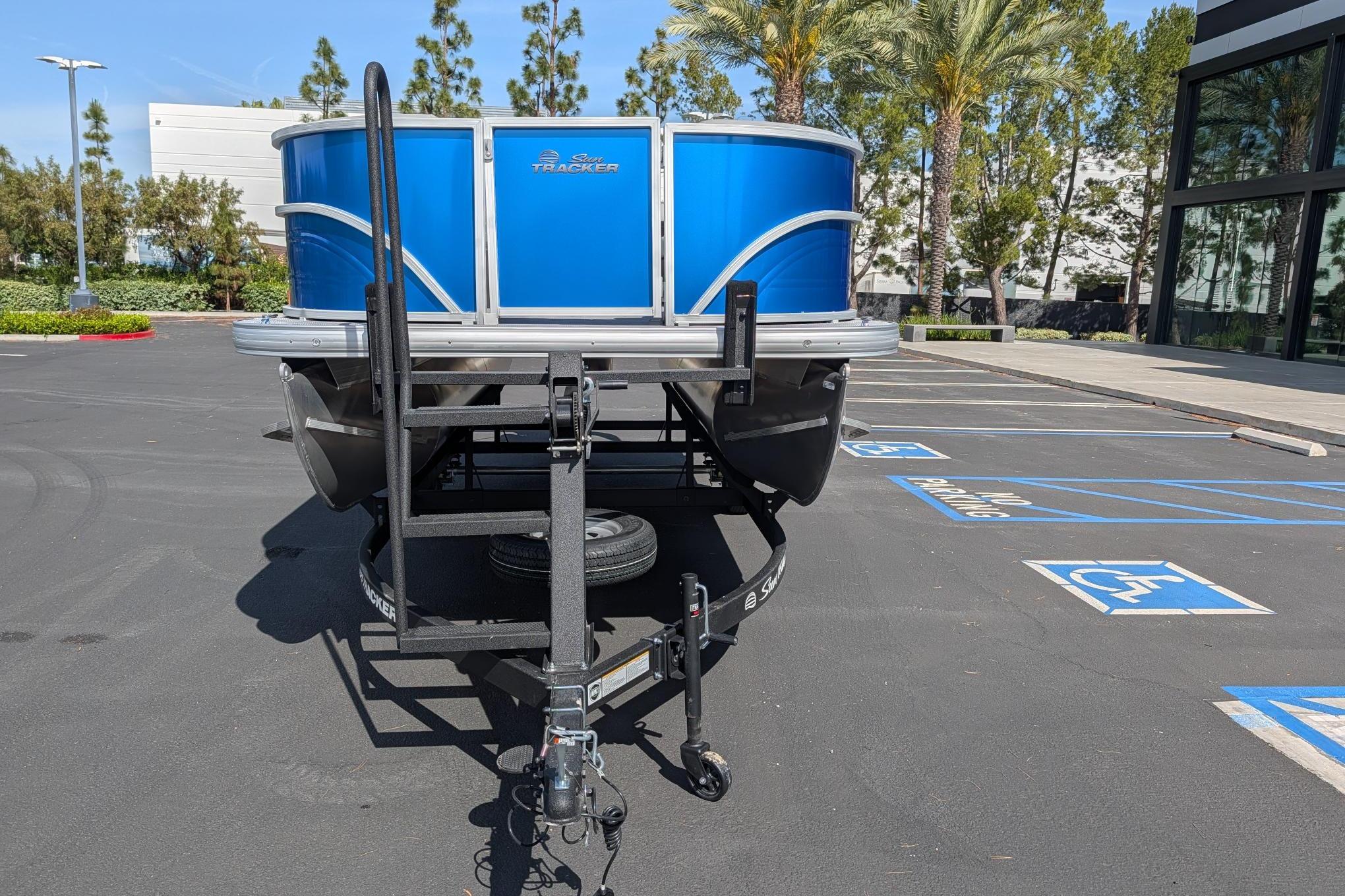 2026 Sun Tracker Party Barge 16 DLX pontoon boat on trailer in parking lot.