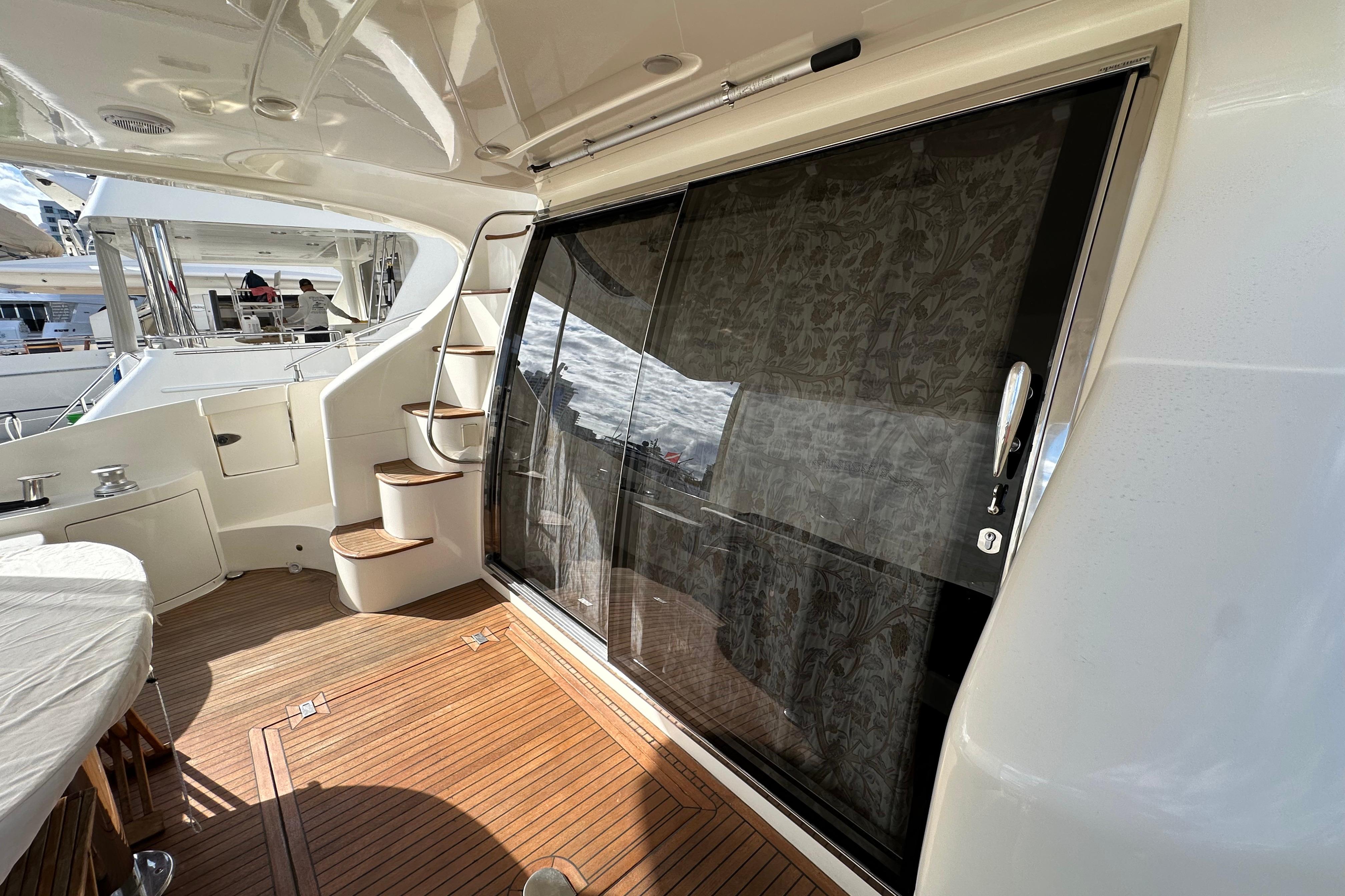 Luxurious 2004 Azimut 55E yacht deck with wooden flooring and elegant sliding glass door.