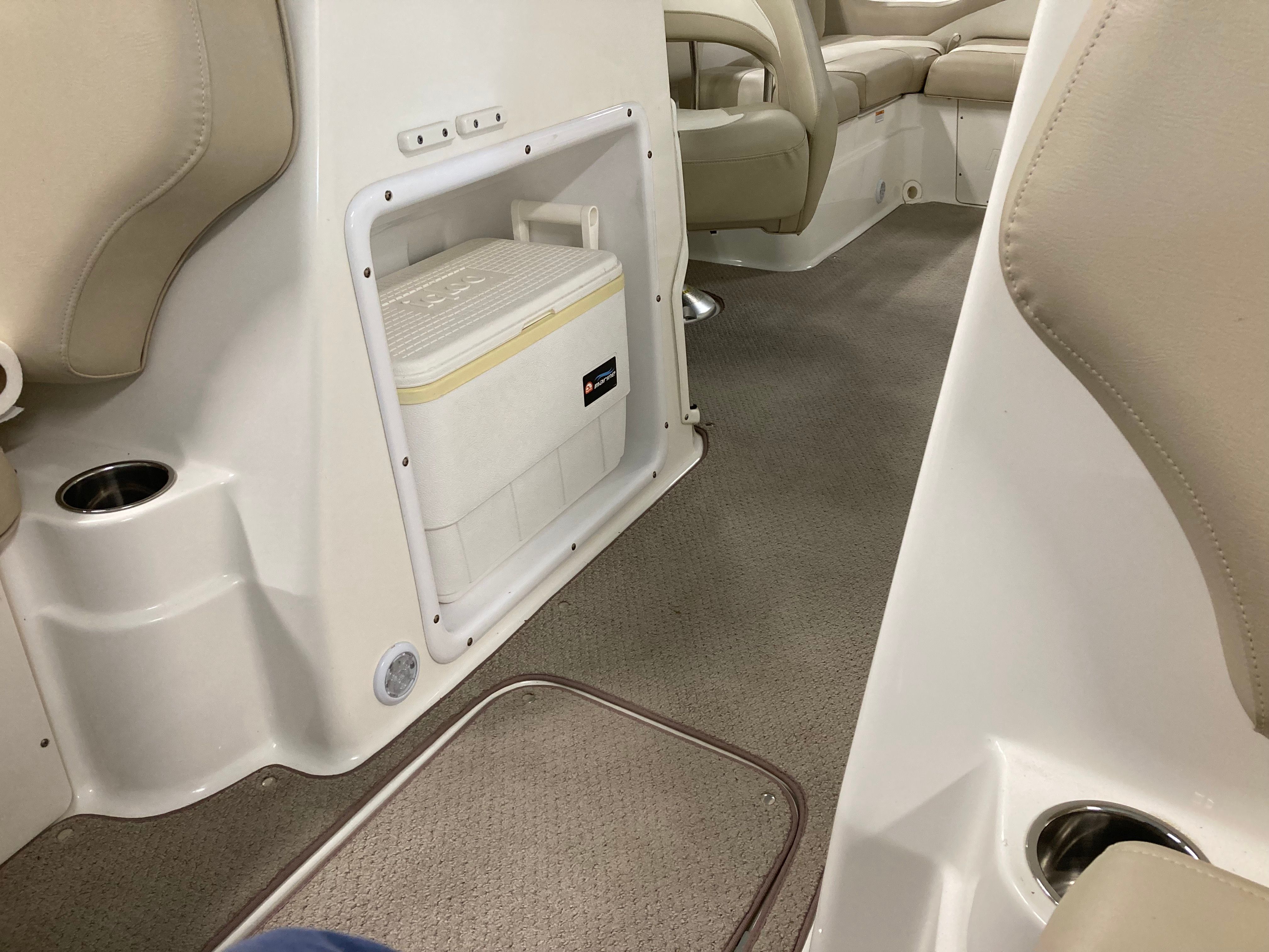 Interior of a 2016 Custom 223 DC boat with beige upholstery and built-in cooler.
