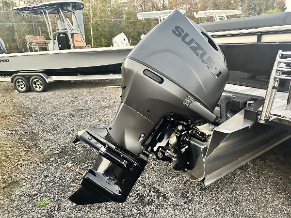 2025 Avalon LSZ Versatile Rear Lounger with Suzuki outboard motor, parked on gravel.