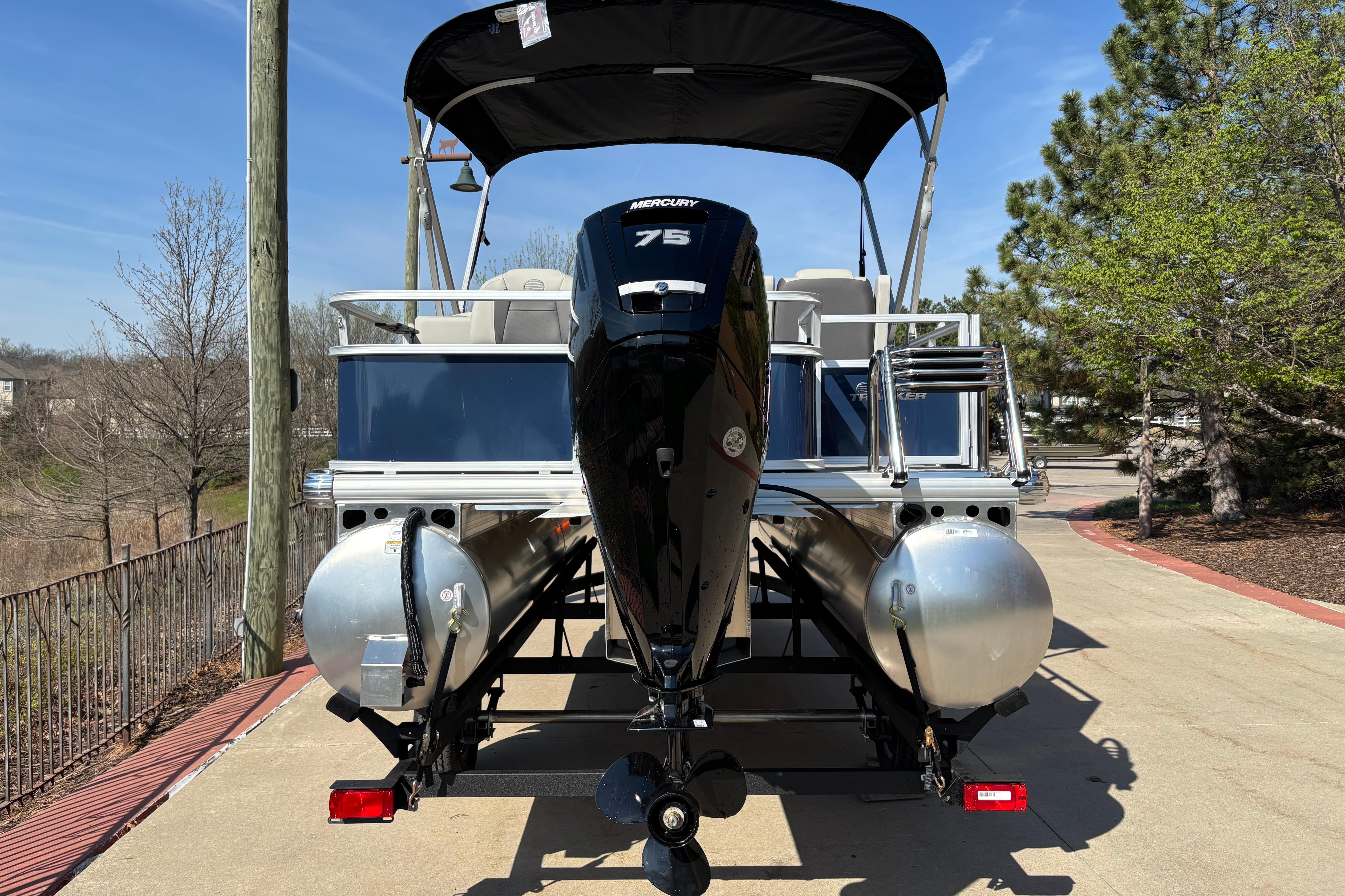2026 Sun Tracker Bass Buggy 18 DLX pontoon boat with Mercury 75 engine, parked outdoors.