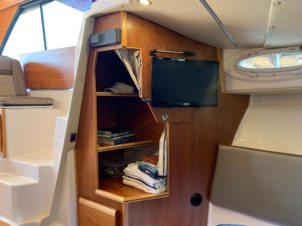 2021 Cutwater C-32 CB interior with wooden shelving, TV, and seating area.