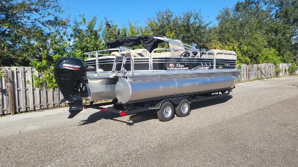2023 Sun Tracker SportFish 22 XP3 pontoon boat on trailer, parked outdoors.
