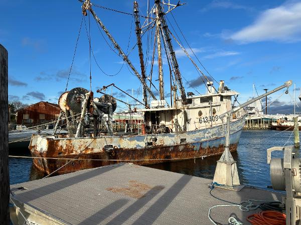Old steel trawler dragger docked at harbor, Custom model, 1979, with visible rust and fishing equipment.